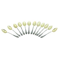 Douze cuillères à café en argent avec coquilles dorées et cartouches en relief.