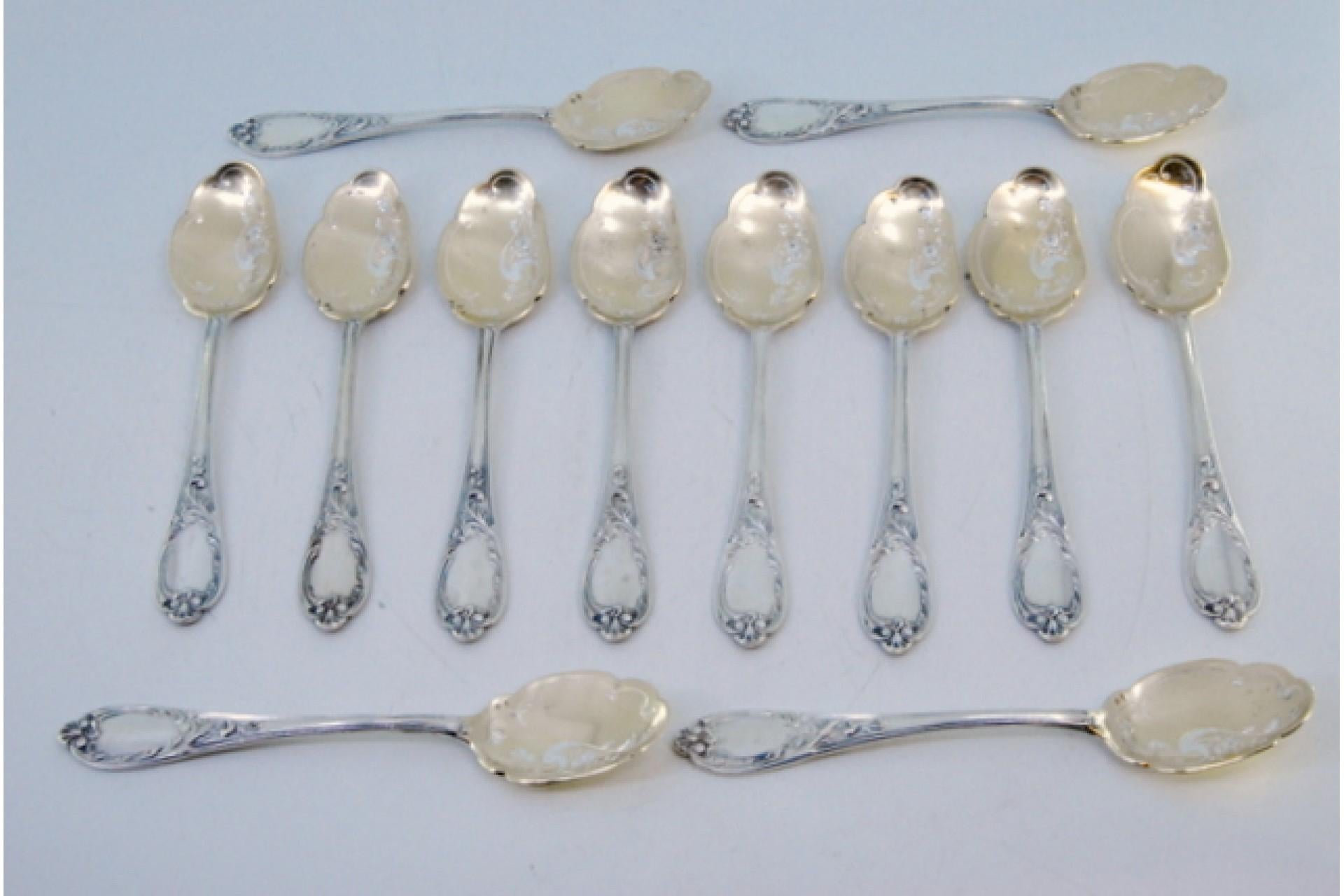 Description: Set of twelve silver ice cream scoops with gold-plated shells and embossed handles. Metal: Silver. Origin: German. Brand: Unknown. Weight: 341.74 grams (Set of twelve scoops). Dimensions: 14x3cm. Content: 833/1000. Assay Mark: Yes.