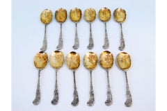 Twelve silver ice cream scoops with gilt engraved shells and raised handles