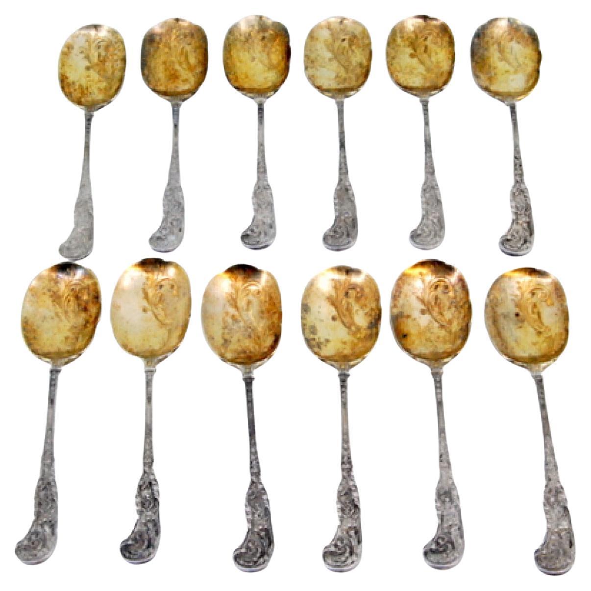 Twelve silver ice cream scoops with gilt engraved shells and raised handles