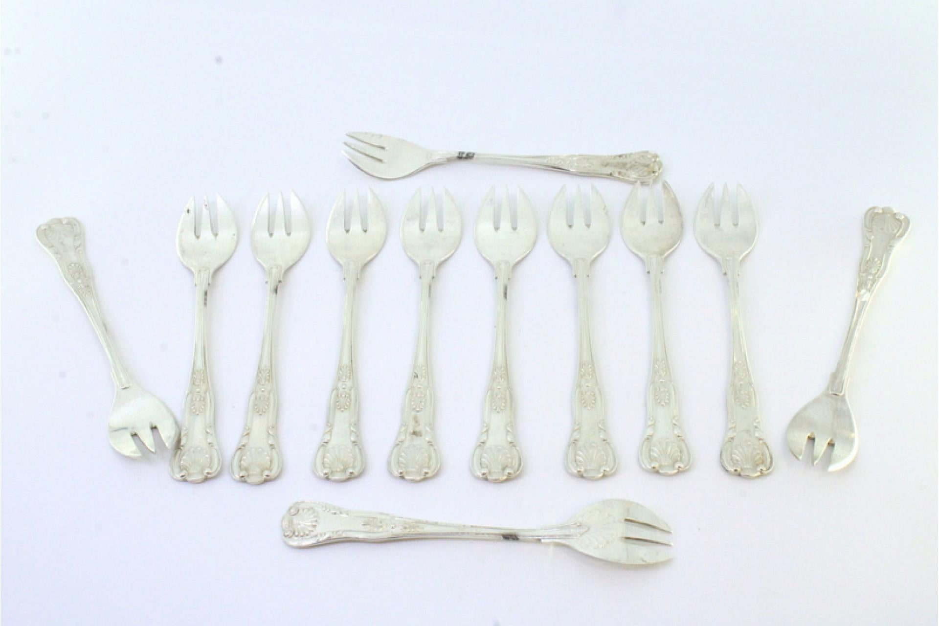 Description: Set of twelve silver oyster forks with revealed and shell-shaped grooves on the handles. Metal: Silver. Origin: Spanish. Brand: Estrela. Weight: 317.04 grams. Dimensions: 2.5cm x 13cm. Content: 915/1000. Assay Mark: Yes. Additional