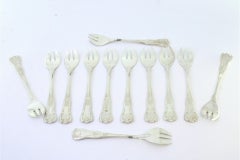 Twelve silver oyster forks with exposed and shell-grooved handles