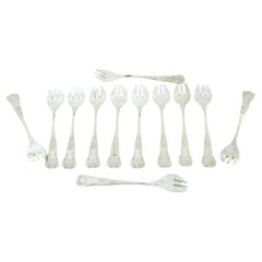 Twelve silver oyster forks with exposed and shell-grooved handles