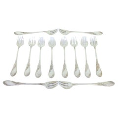 Twelve silver oyster forks with reliefs and monogrammed three-prong design