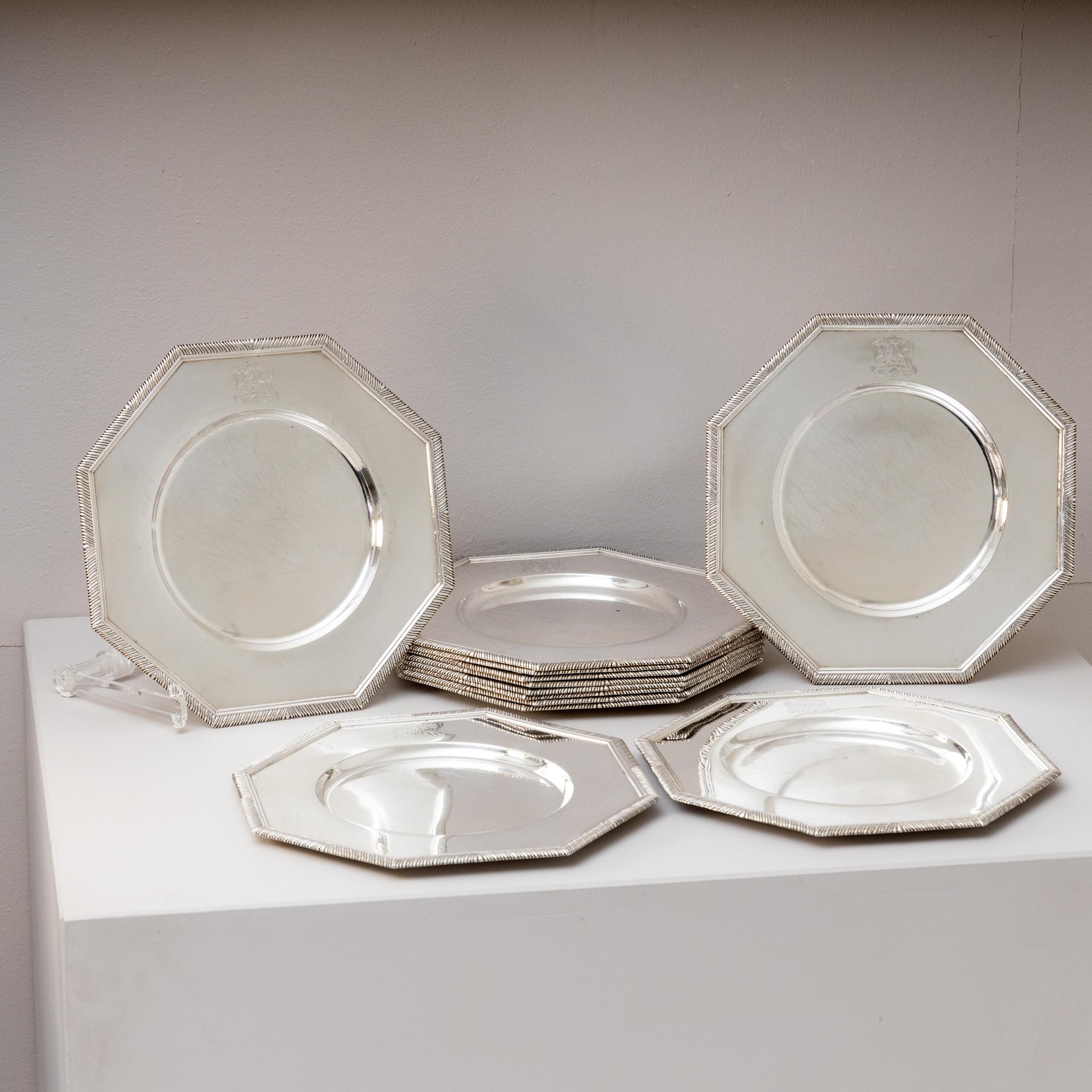 Set of twelve silver plates in octagonal shape and round mirror. Each plate is decorated with a coat of arms with the motto 