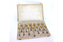 Twelve silver spoons and shovel with fleur-de-lys handles and gilt shells