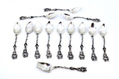 Twelve silver spoons and sugar shovel with cut relief handles