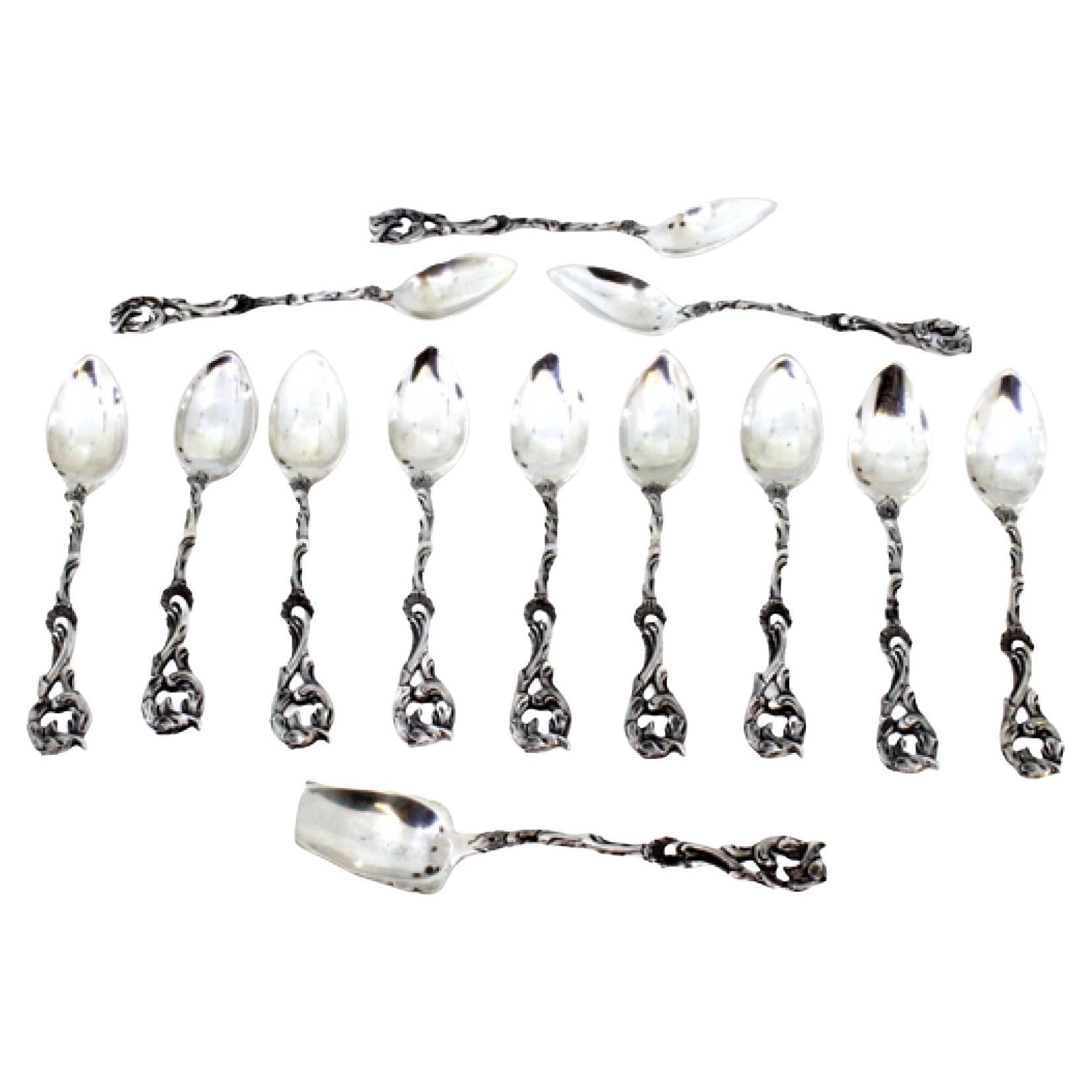 Twelve silver spoons and sugar shovel with cut relief handles
