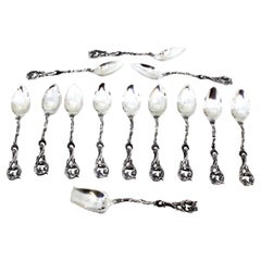 Twelve silver spoons and sugar shovel with cut relief handles