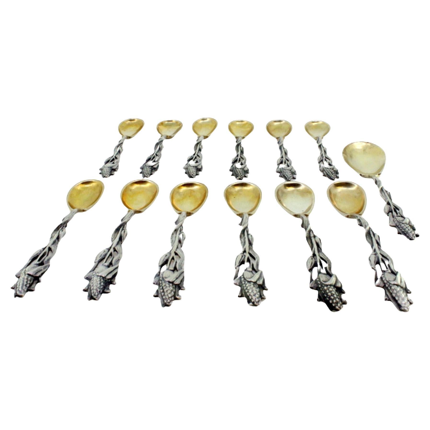 Twelve silver teaspoons and sugar shovel with corn-cob reliefs and gilt shells
