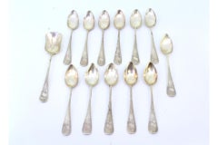 Twelve silver teaspoons and sugar shovel with floral relief monograms