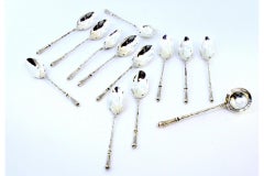 Twelve silver teaspoons and sugar shovel with friezed relief handles