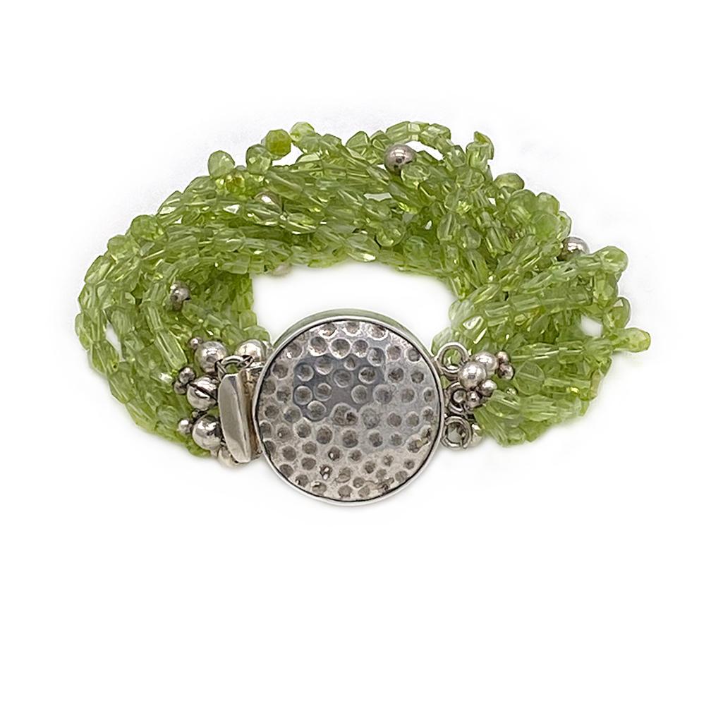 This is a twelve strand peridot bracelet created by Nouveau Boutique. We had to take much time to work with these tiny faceted variable shaped translucent peridot gemstone beads. Some sterling balls and other sterling components are scattered among