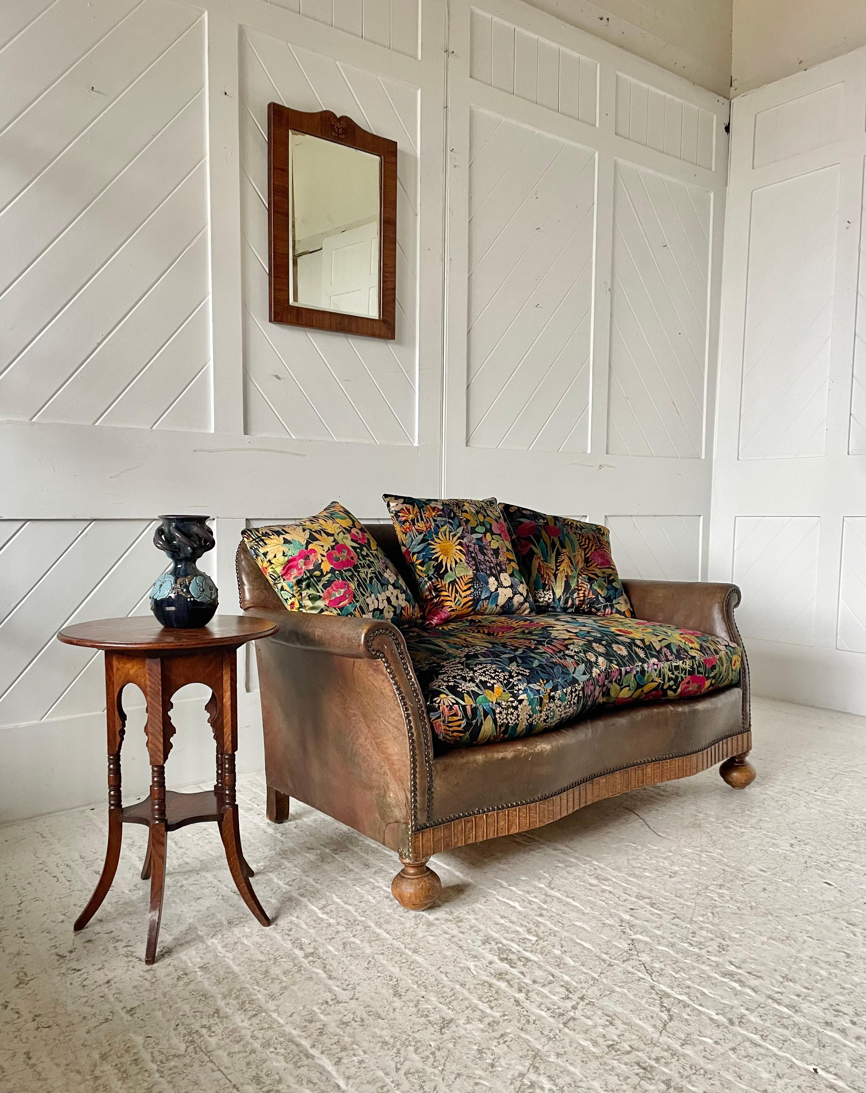 Un bellissimo divanetto da cottage. Grembiule anteriore a serpentina in Oak e piedi a castello con cuscino originale in pelle e tessuto in velluto Fabrice di Liberty London.
