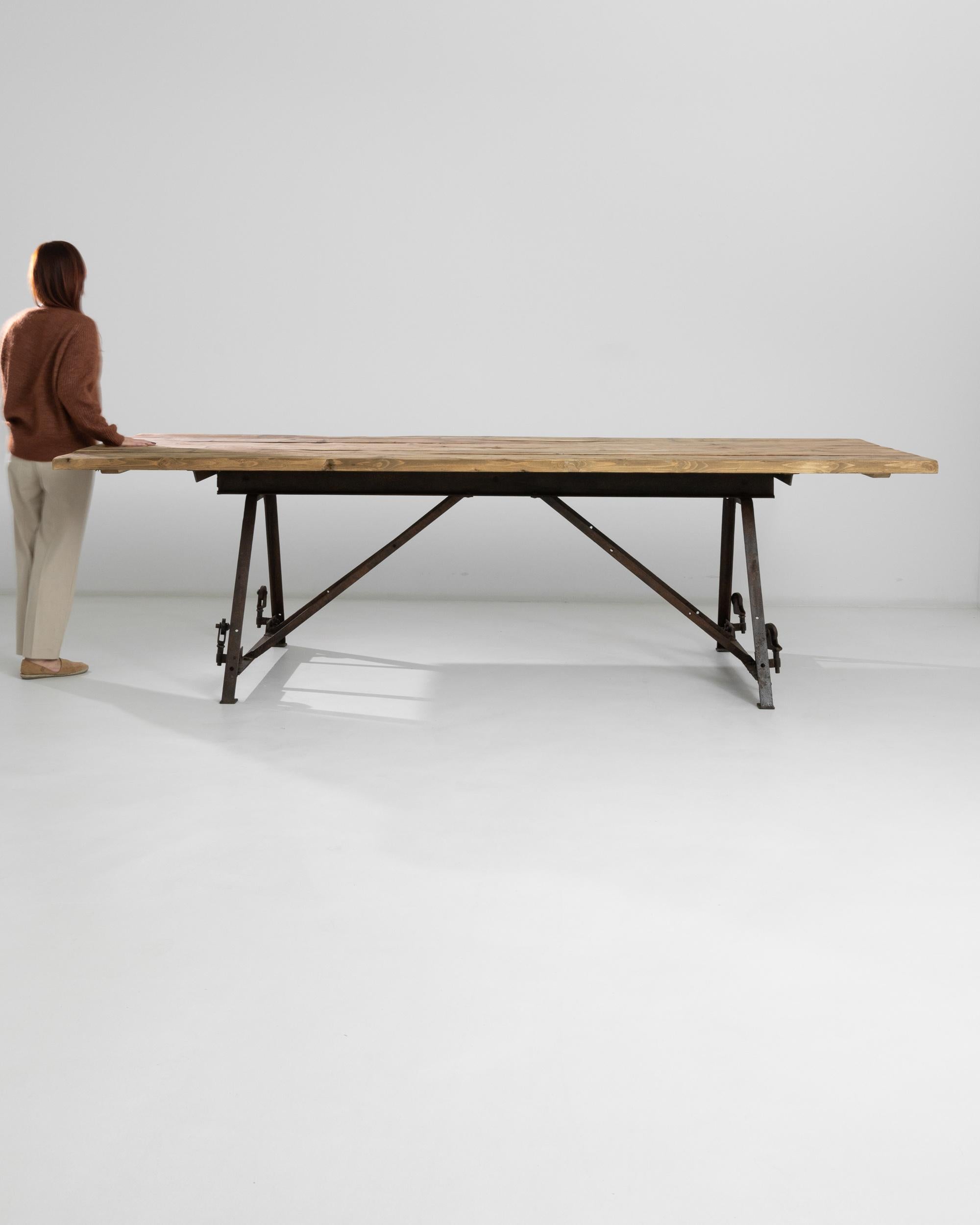 A heavy duty French wooden and metal table from the twentieth century. This large table is constructed from sturdy wooden planks and steel angle rods, giving it an angular and wirey demeanor. Elegantly industrial, this unique table could seat a
