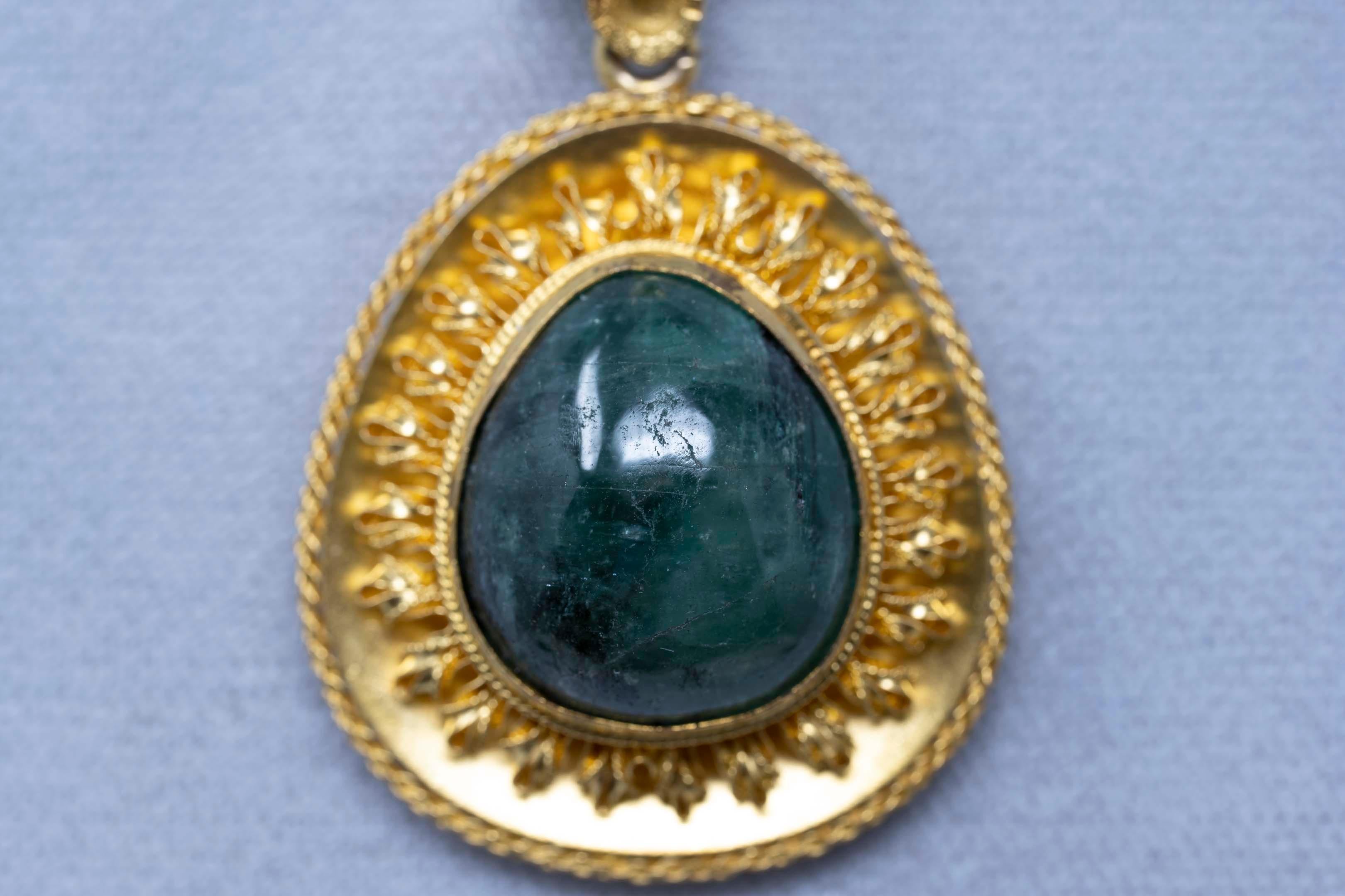 One (1) ladies pendant, in yellow, 14k gold (by acid test), fantasy style, worked finish, the total weight is 9.5 grams. The item is set with one (1) natural beryl emerald, pear cabochon cut. Approximate weight 20 carats, measurements 20 x 17 mm