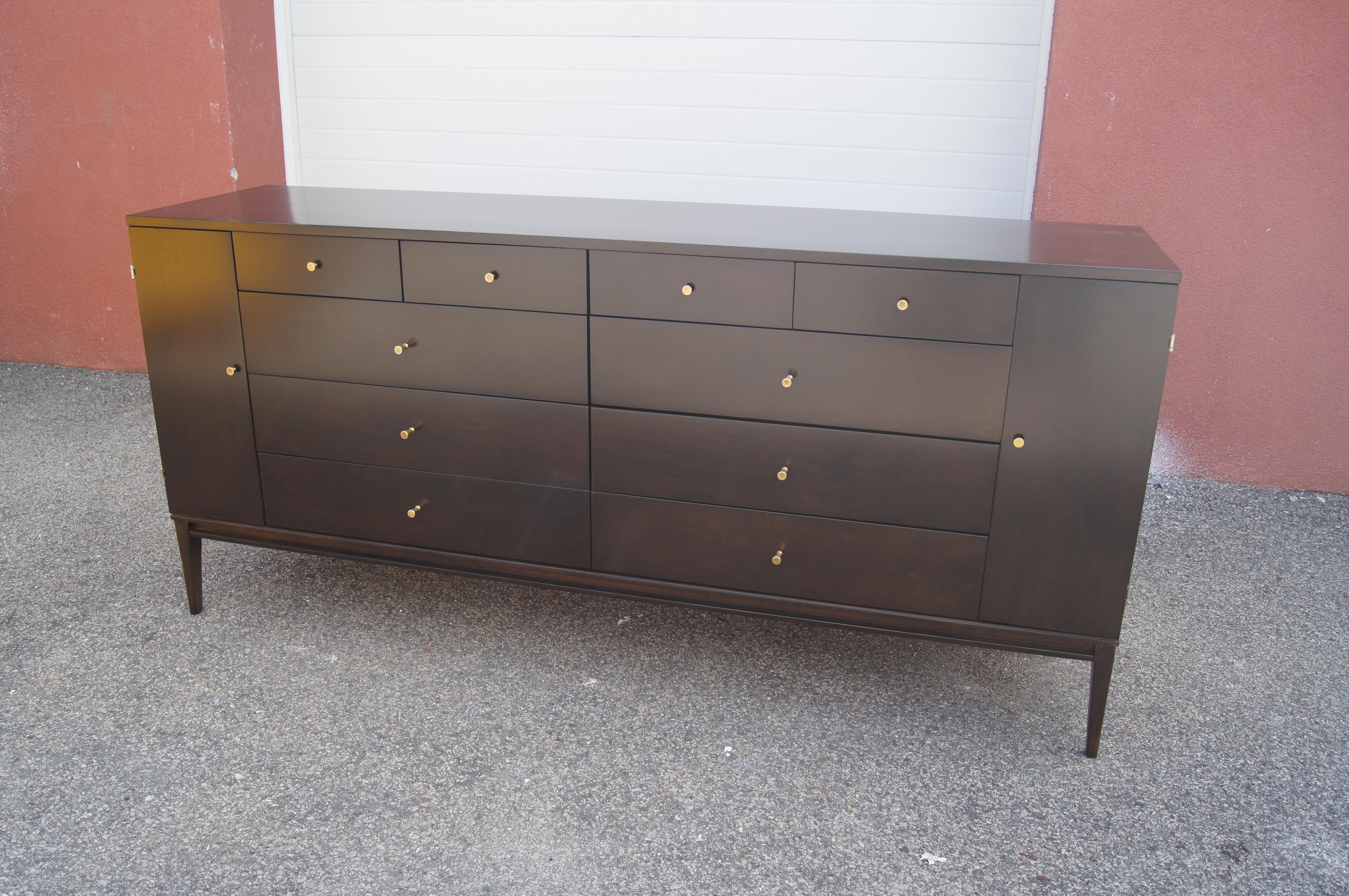 Designed by Paul McCobb for Rapid's Furniture of Massachusetts, this handsome dresser is made of solid maple with a dark lacquer finish. Sitting on tapered legs, the case offers a total of twenty drawers. In the center are four small drawers above