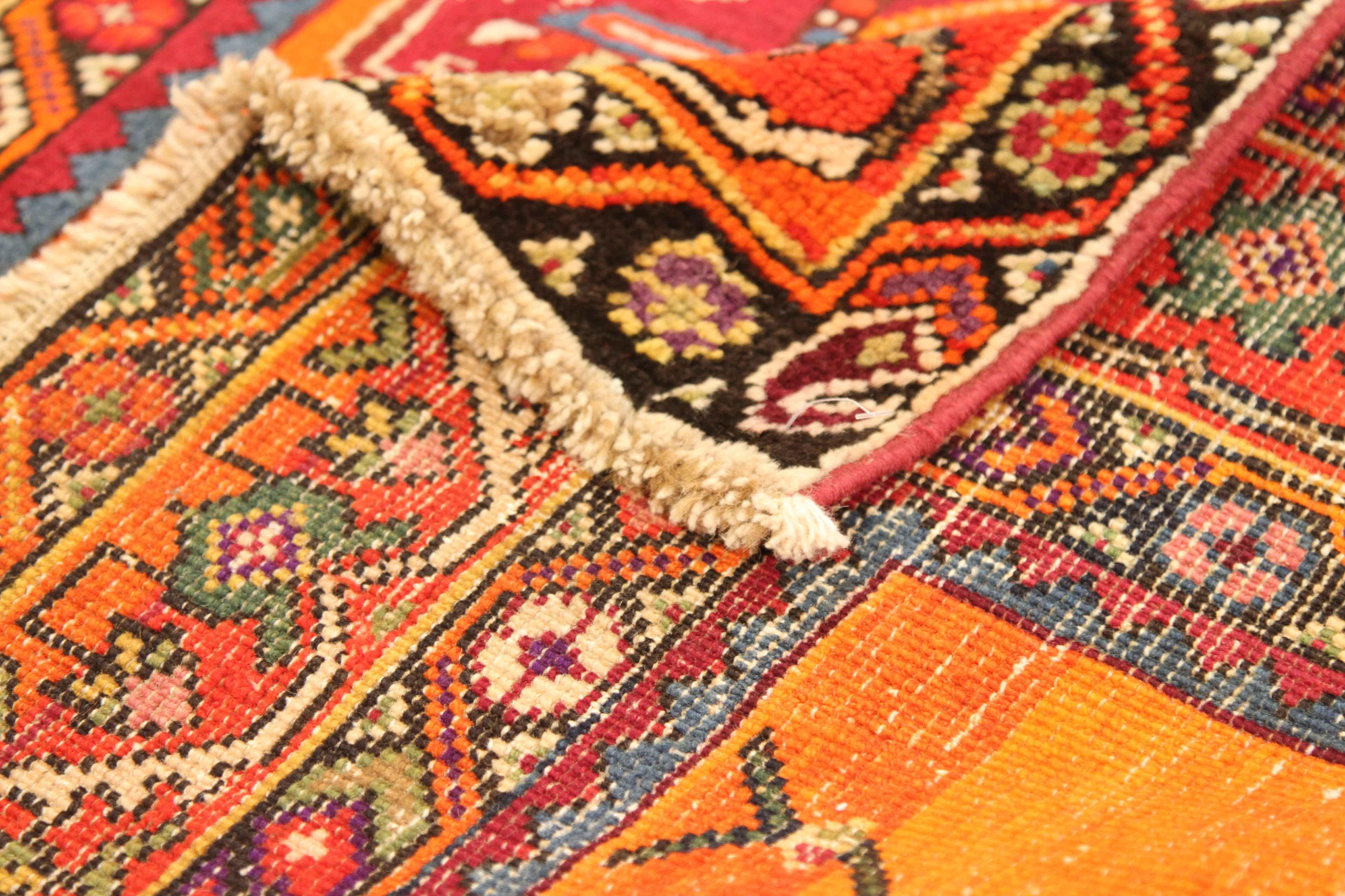 Handmade in the 1950s from the best quality of wool and vegetable dyes. The antique Persian rug was given the bold color palette of red, black, blue, and orange to highlight the large green gemstone details on the field. Karabagh weavers became