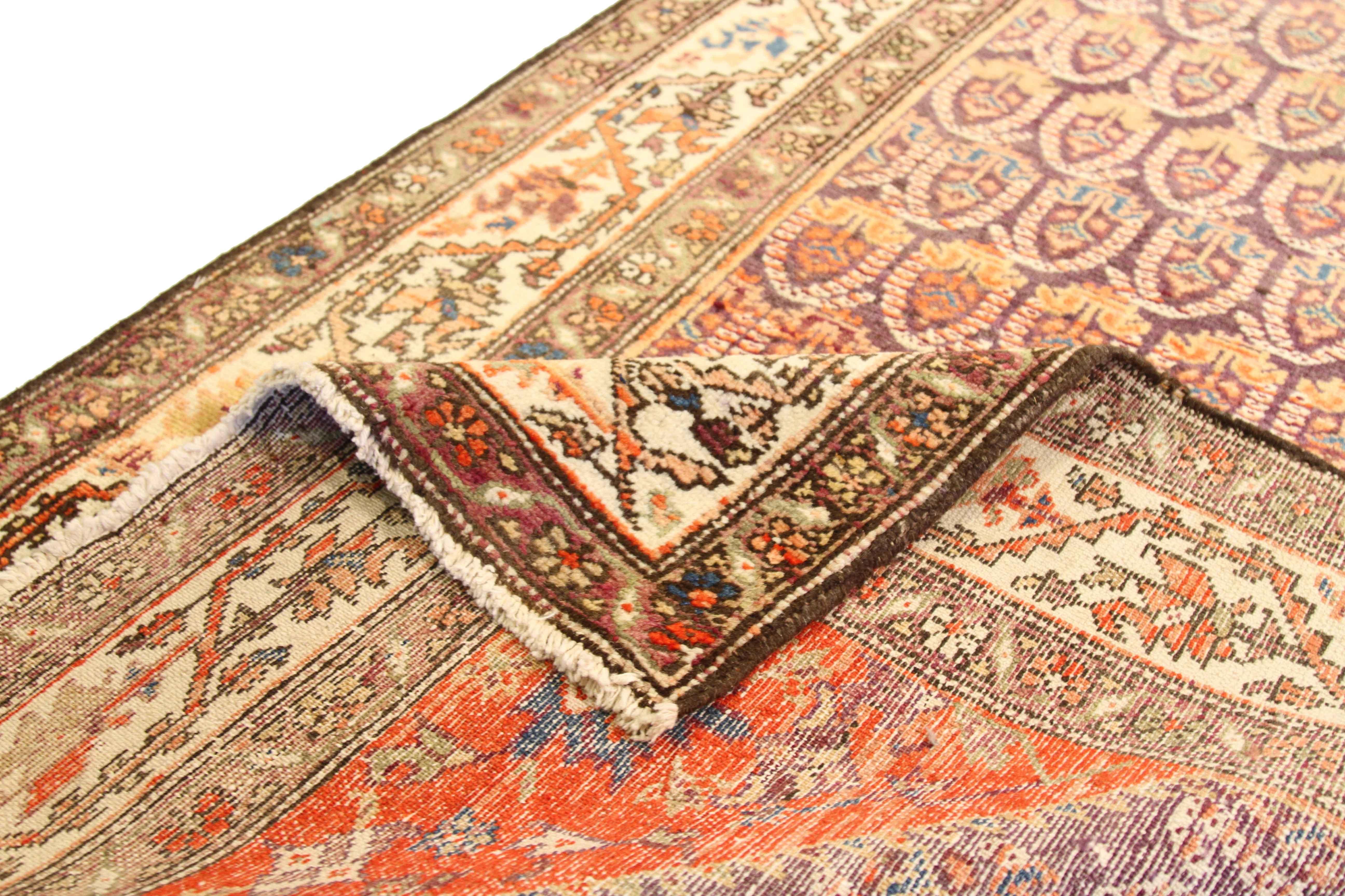 Made from handspun fine wool and organic vegetable dyes, this antique Persian rug features repeating patterns of traditional emblems reminiscent of ancient Persian royalty. The blend of majestic hues like purple, ivory, green, and red make it an