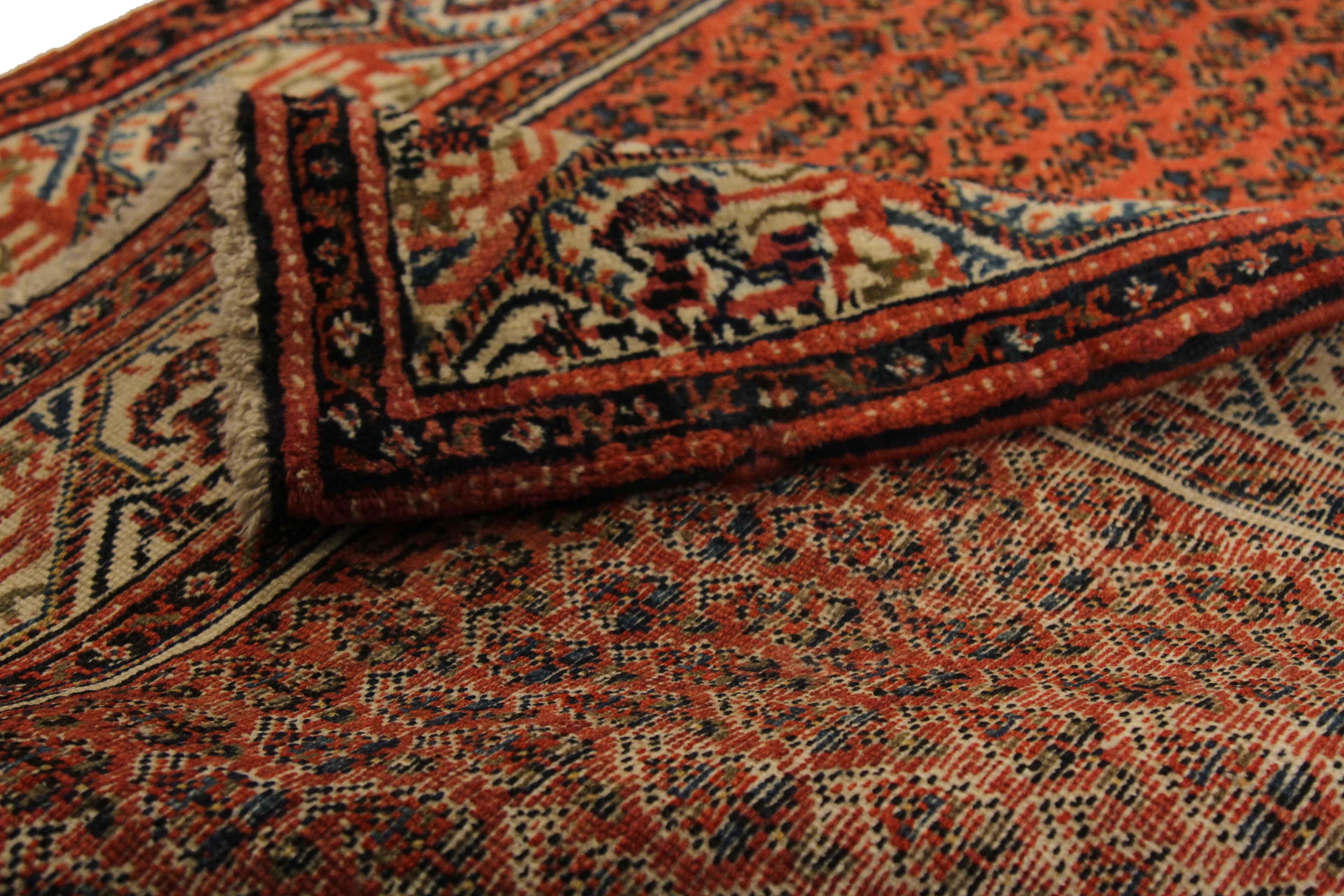 Finely woven by hand using exquisite wool and vibrant vegetable dyes, this antique Persian rug features a wide, open field of ‘boteh’ or leafy patterns popular in Saraband made carpets. Weavers skillfully blended red, black, ivory and blue to make