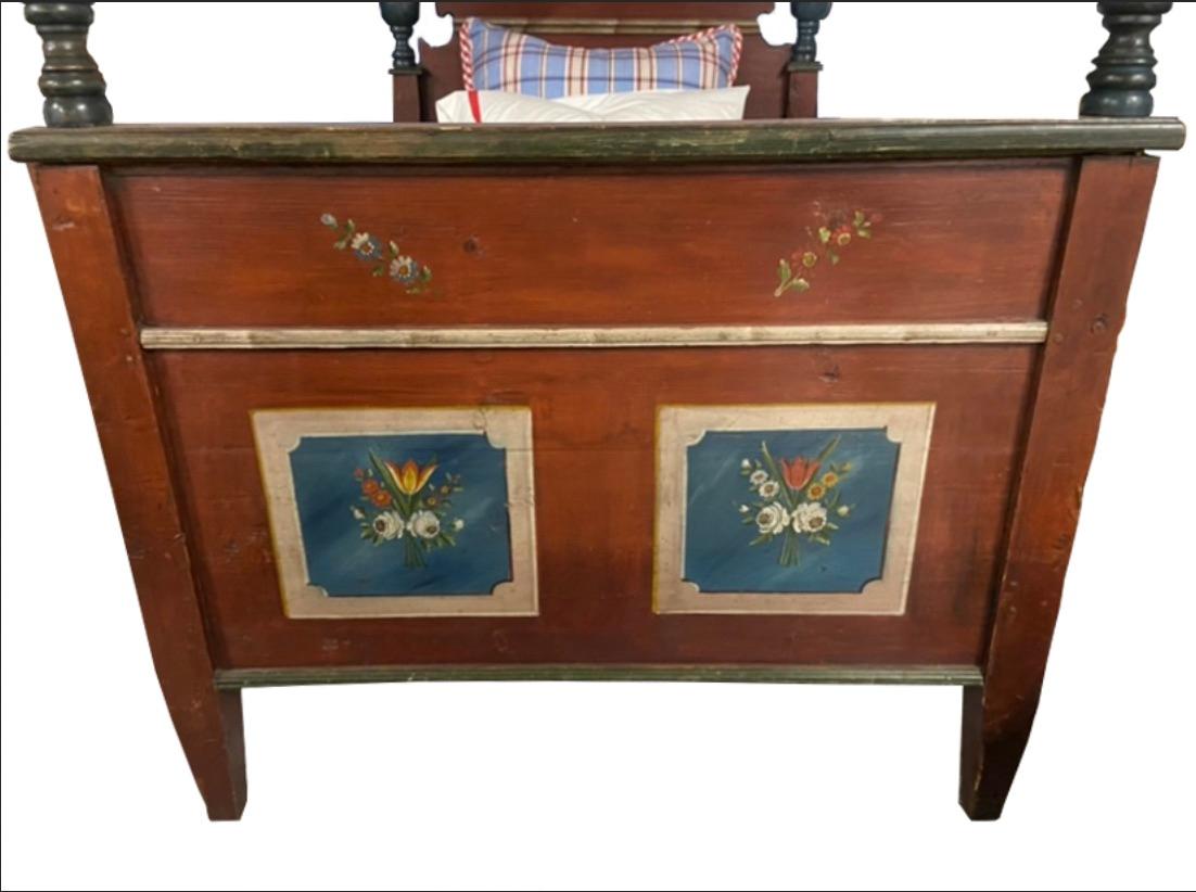 A delightful, folk art single bed most likely Hungarian, hand initialed and dated “C.F.B.” and “1834”.

Frame painted burnt red with turned multi-colored posts, headboard and footboard featuring framed bouquets of flowers.

Blue and burnt red