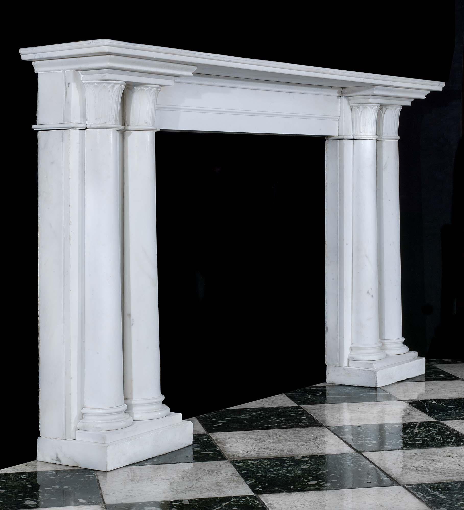 An elegant twin columned Regency chimneypiece in white statuary marble. The wide moulded shelf, above a plain frieze, rests on two pairs of half round tapering columns with finely carved acanthus capitals and demilune stepped feet, English, circa