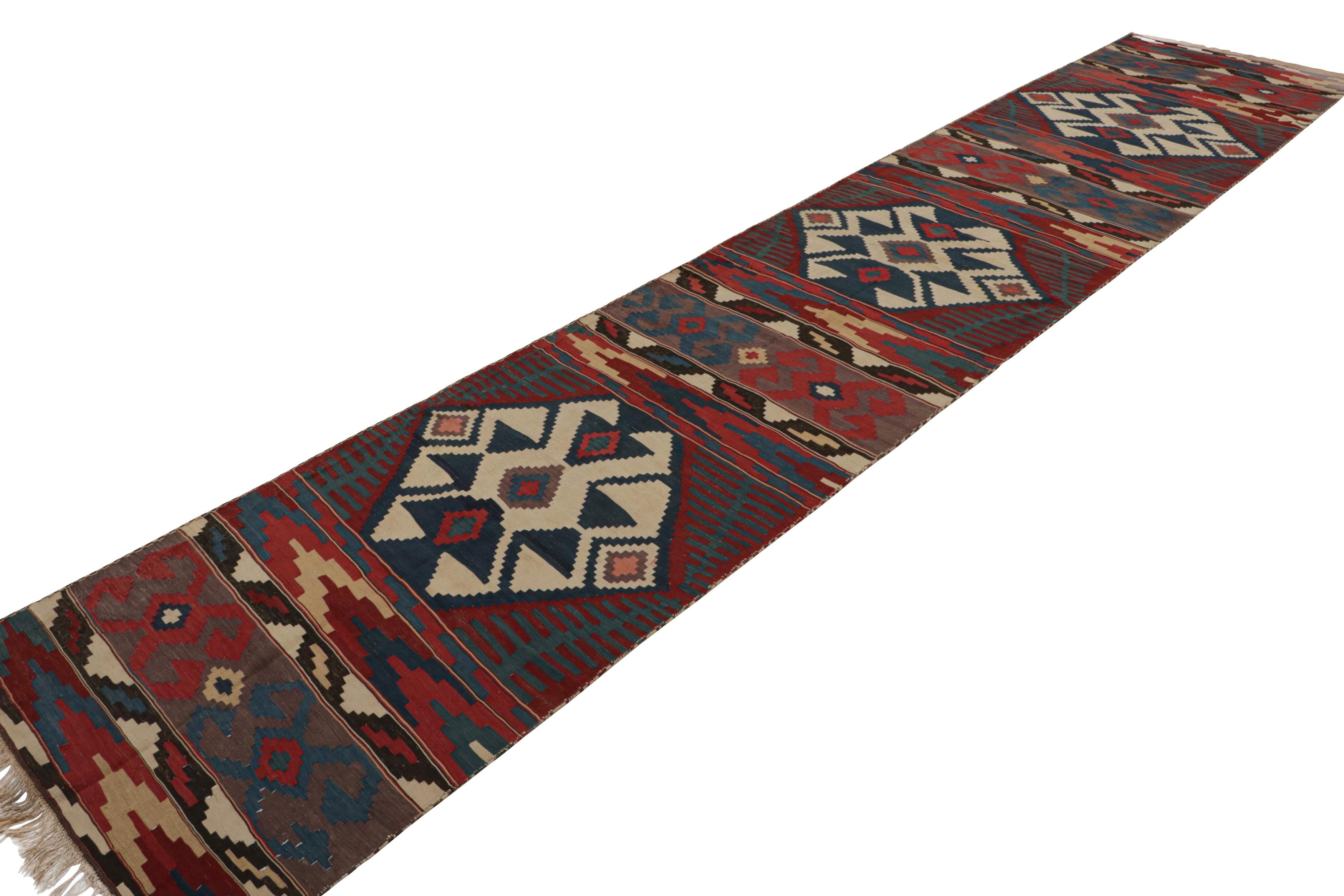 This flatweave is from a rare pair of twin 3x17 vintage Persian Kilim runner rugs, hand-knotted in wool circa 1950-1960. These tribal runners are nearly identical in size and design, with geometric patterns in red, blue and beige tones. 

On the