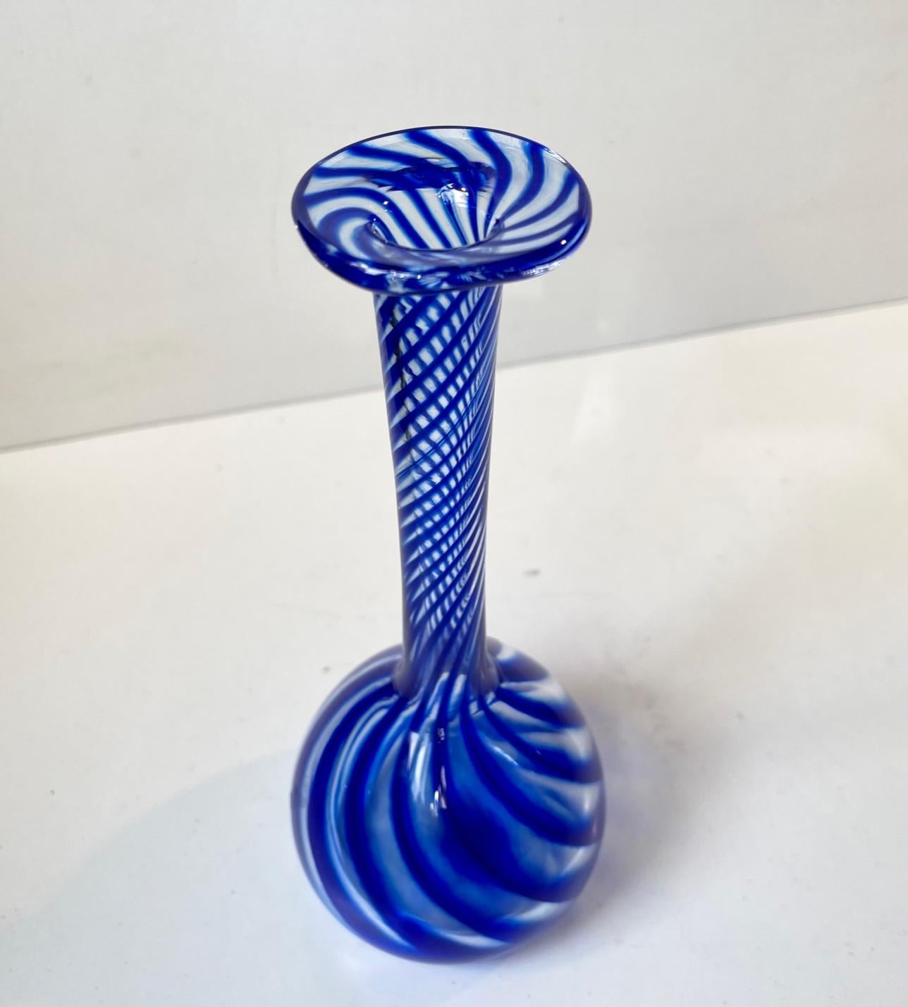 A handblown long-neck art glass vase in cobalt blue and clear. It is called Solitaire (Da: Solitær) and was made by glass artist Martin Birk Møller in his workshop Glashütten in Nykøbing Sjælland Denmark. The paper sticker is still present to the