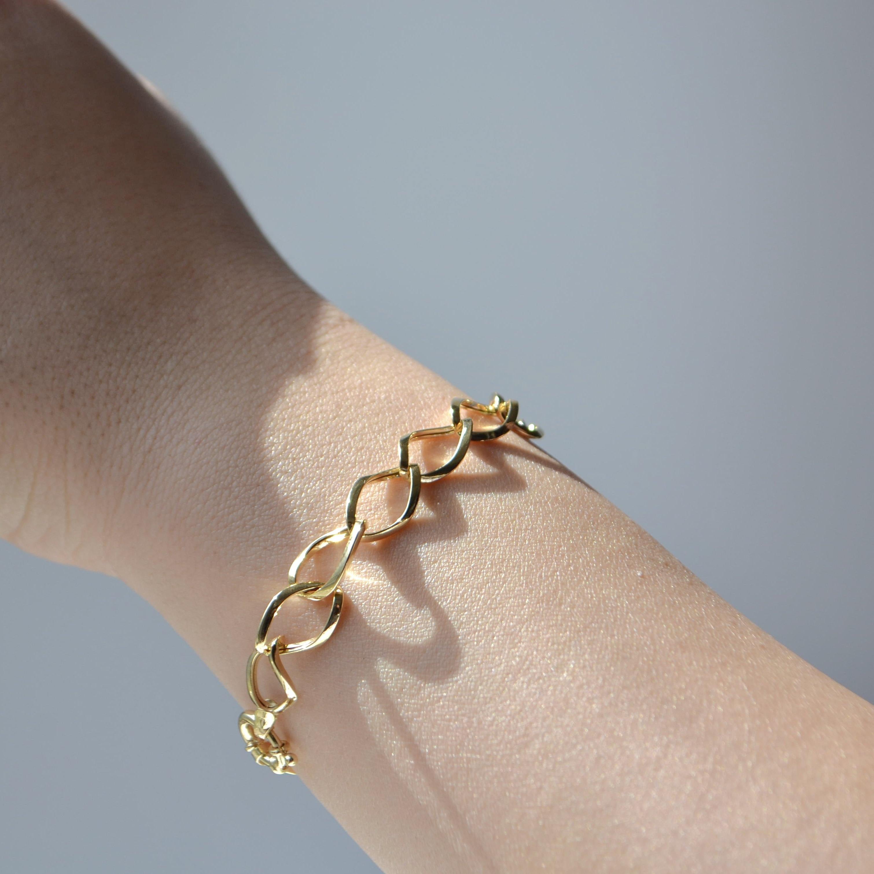Realizzato in oro giallo 18 carati, questo elegante bracciale presenta un design a maglie fluido e scultoreo che evoca movimento e modernità. Ogni maglia aperta a forma di marquise è graziosamente incastrata, creando una silhouette elegante che