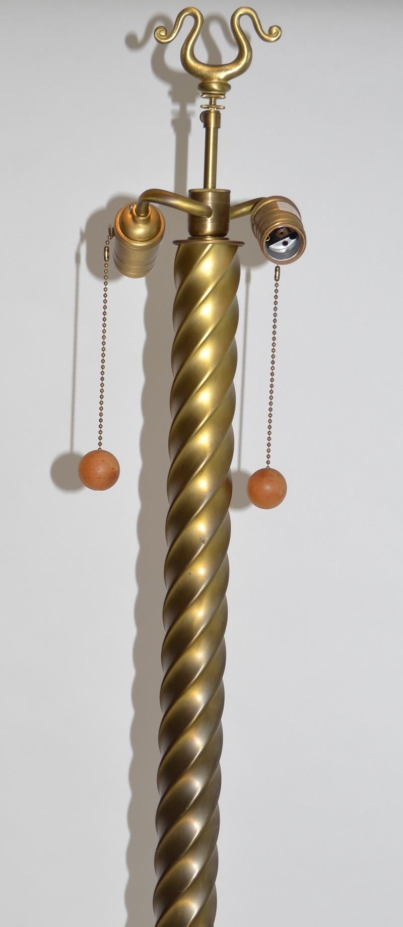 Metal floor lamp by Angelo Donghia c. 1990's. Gloss brass or gold finish. Twisted form with two sockets, square base on ball feet, cloth cord, decorative finial. No shade.