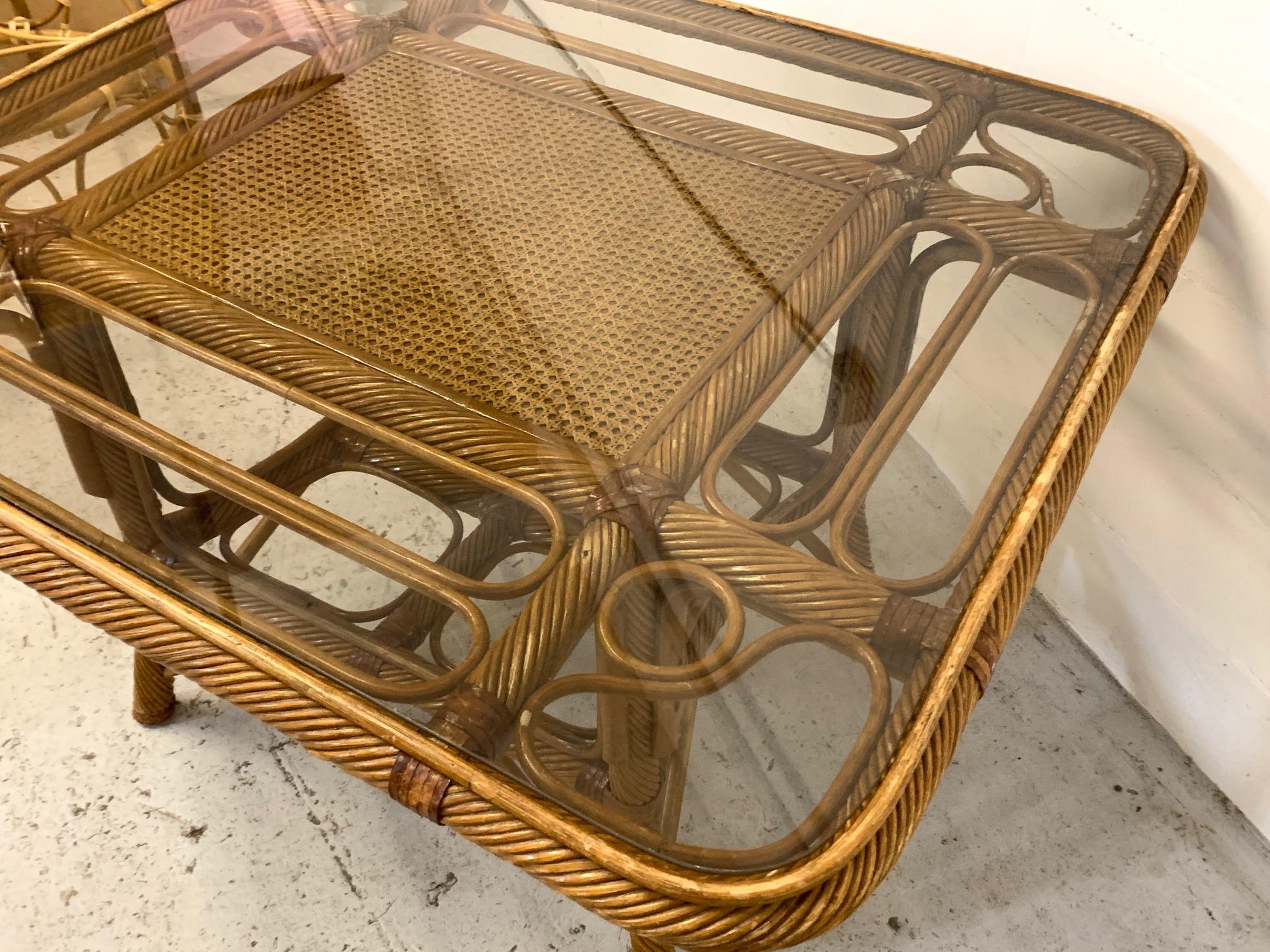 Vintage rattan dining table features cane and twisted reed detailing and a glass top. Good vintage condition with minor imperfections consistent with age.