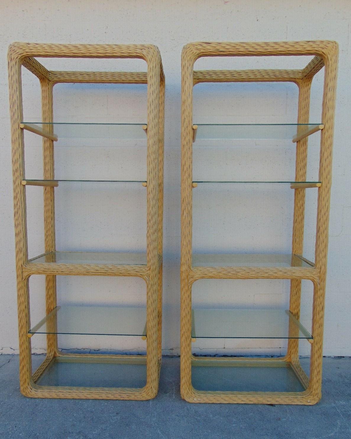 A pair of organic modern twisted rattan etageres, circa 1970s. These expertly handcrafted etageres, each with five glass display shelves designed within a braided rattan frame, offer a convenient and attractive space to display books, objects and