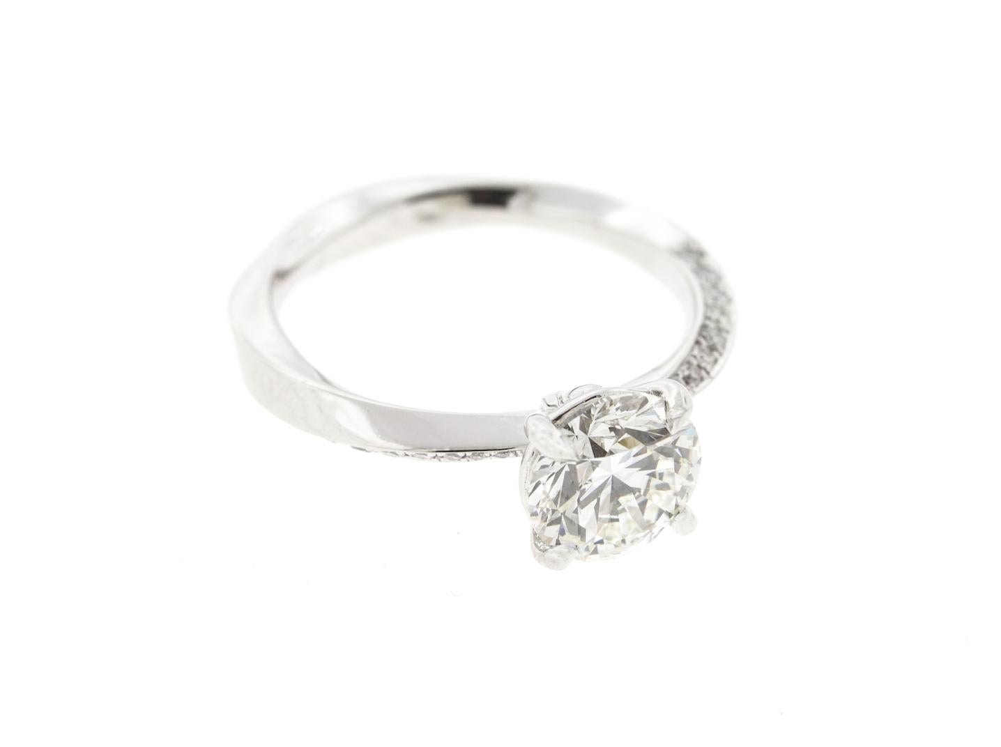 This custom diamond engagement ring features a twisted shank and half diamond pave around the band. With a round diamond center stone and a four prong setting, the ring has a head-on shank setting and can be customized for any shape center