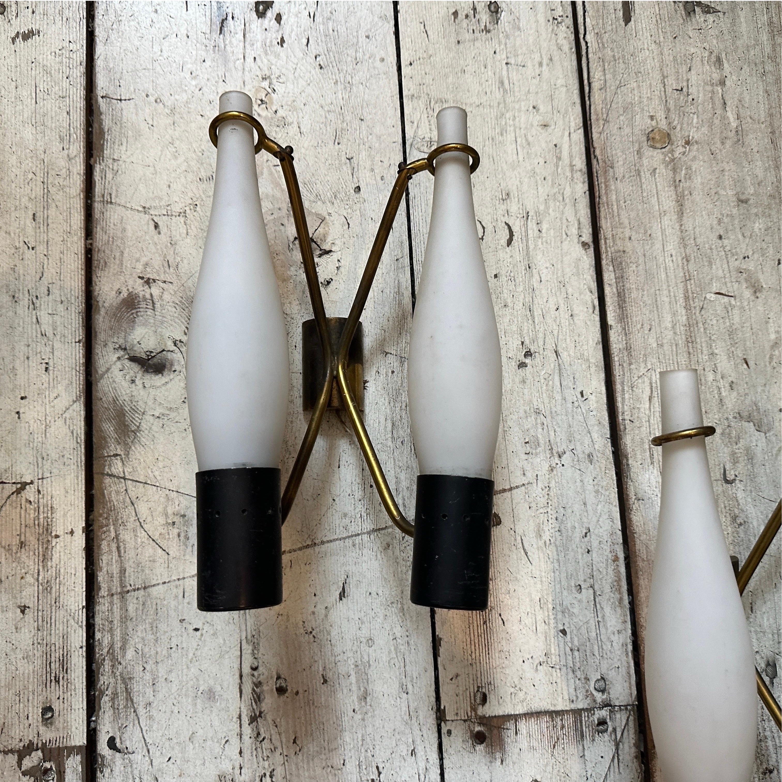 Se trata de dos apliques de pared modernos de mediados de siglo de la década de 1950, diseñados en estilo Stilnovo, un fabricante italiano conocido por su estética elegante y moderna y por el uso innovador de los materiales. Cada candelabro tiene