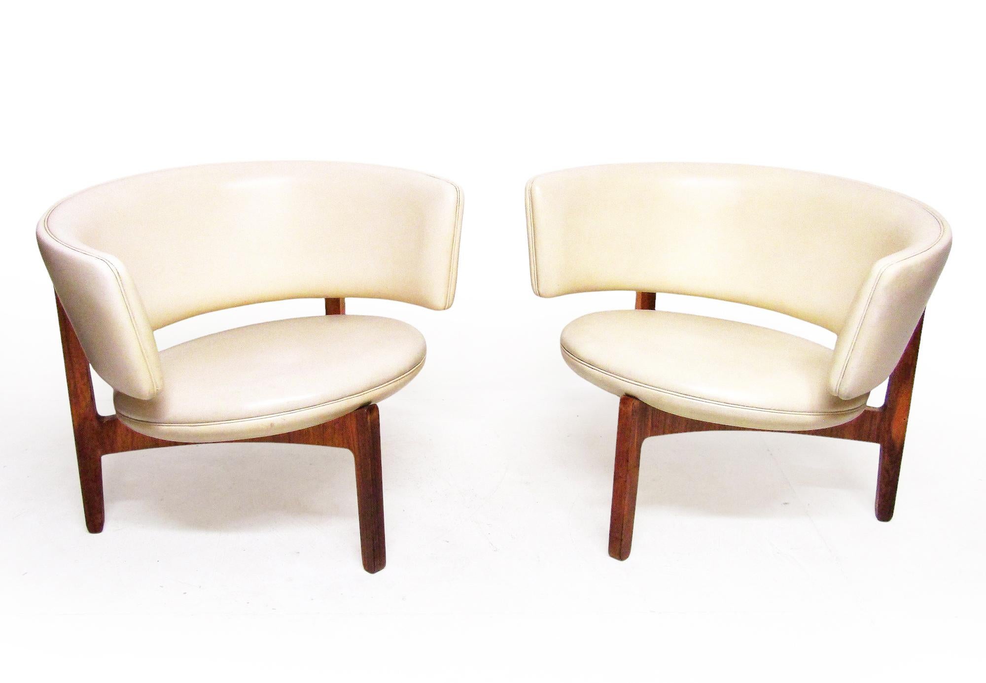 A pair of two lounge chairs designed by Sven Ellekaer and produced by Christian Linneberg Møbelfabrik in Denmark, circa 1962. They are offered individually.

The striking crescent backs and circular pod seats are upholstered in rare ivory-white faux
