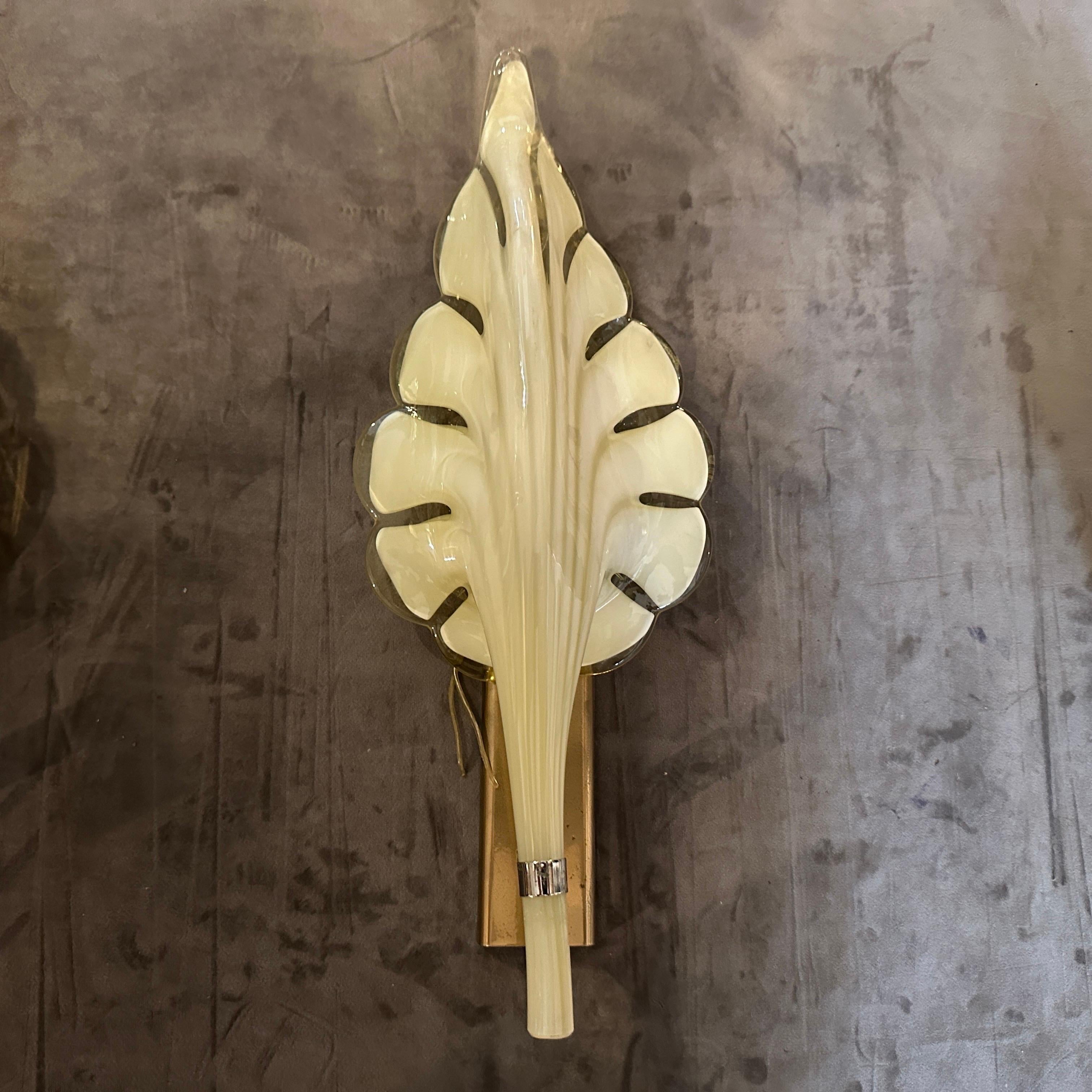 These are 1970s Mid-Century Modern murano glass wall sconces designed by Franco Luce. The sconces feature a striking leaf-shaped design made of hand-blown clear and Yellow Murano glass, with a translucent finish and soft curves that create a warm