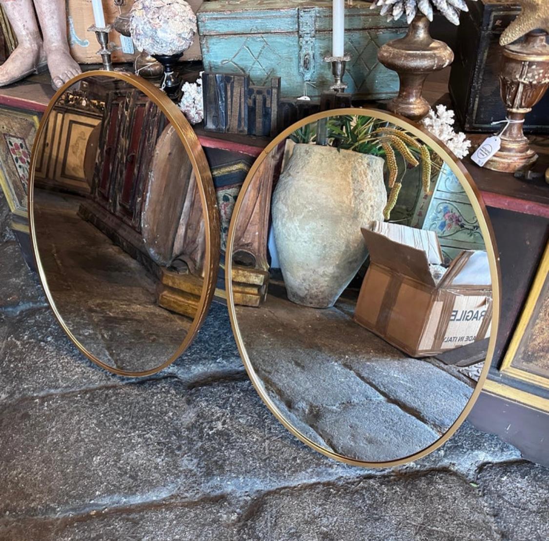 Two gilded aluminum mid-century modern oval shaped wall mirror hand-crafted in Italy in the Eighties in the style of Gio Ponti, glasses have been changed. This set of oval wall mirrors is a stunning and elegant piece that captures the essence of