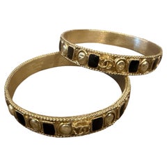 Two 1990s Iconic Gold Plated Metal and Black Enamel Bangle Bracelets by Chanel