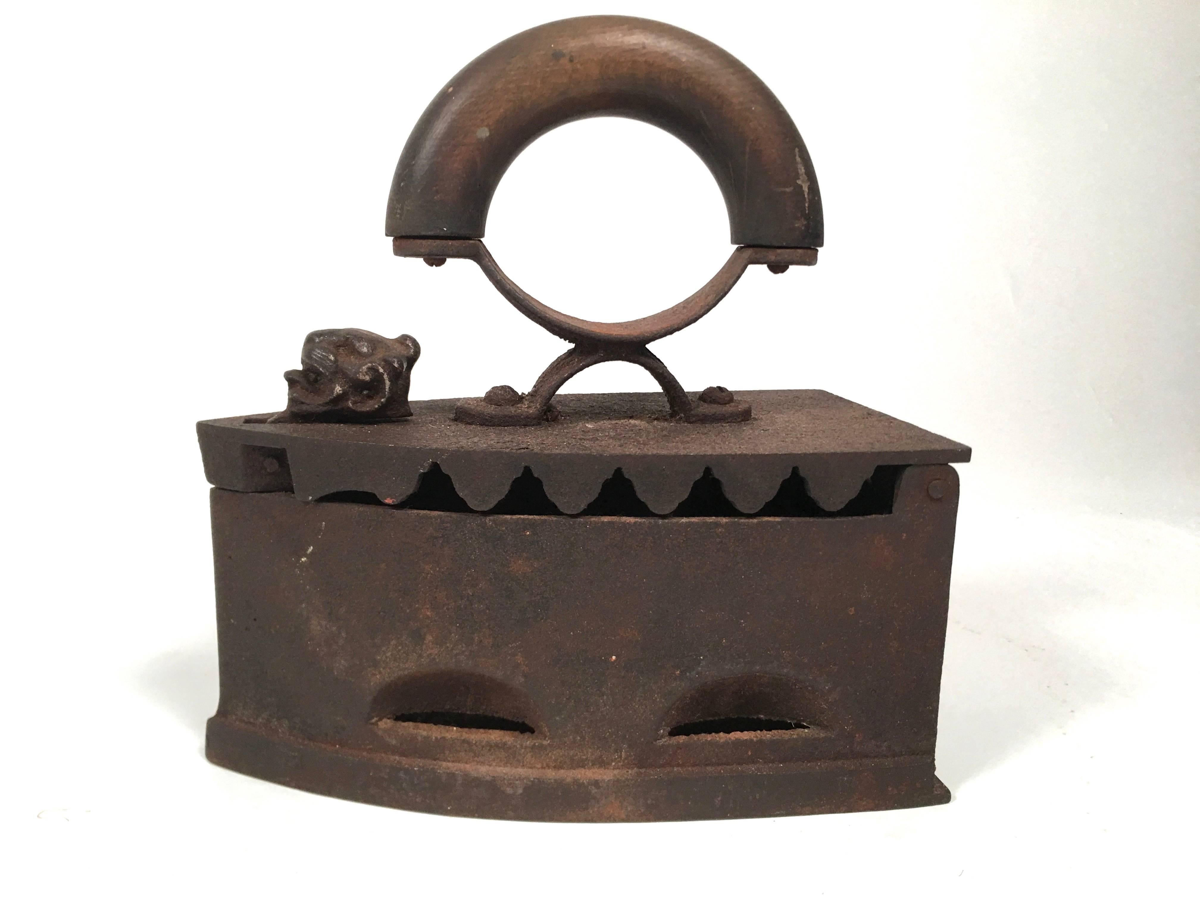 Two 19th century sculptural and decorative cast iron coal irons, one decorated with a lion's head, the other with a rooster's head, of typicalform with flip-top to store coal inside and wooden handles, one curved, the other turned and painted red.