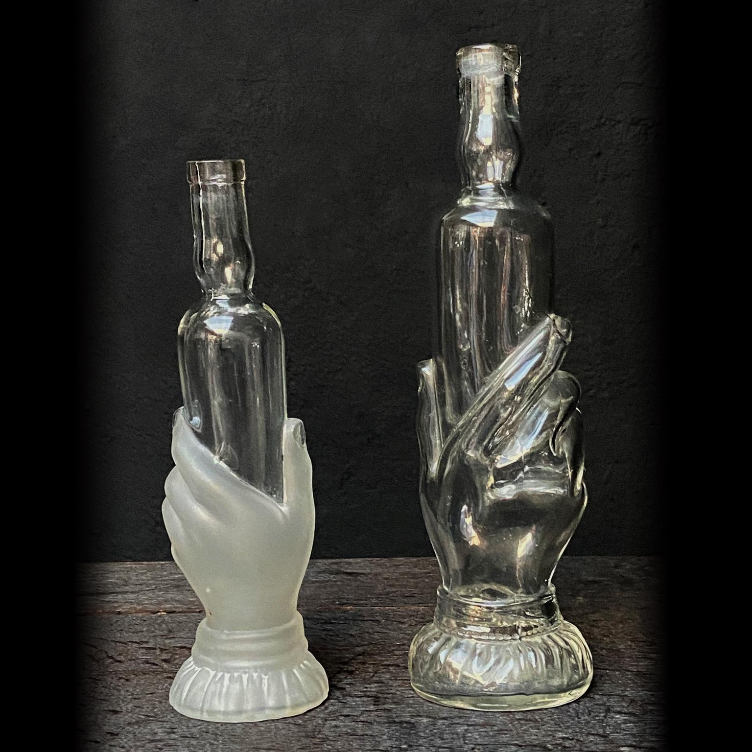 Set of two beautiful bath soap, foam or beauty oil bottles. The hand shaped bottles have beautiful details like cuffed and buttoned sleeves from which the hands appear, holding an elegant shaped bottle. 
All bottles are blown by hand as they clearly