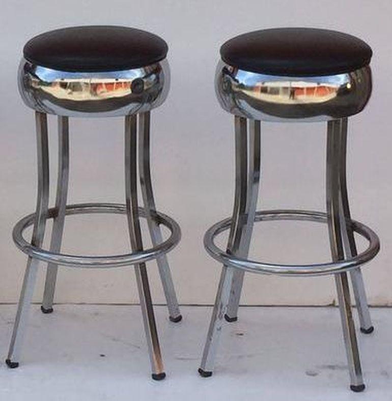 A vintage American bar stool of chrome steel, with stationary seat of chrome with vinyl upholstery, resting on four leg stretcher support, each leg with rubber stop.

Two stools available. Priced individually - $1295 each bar stool.