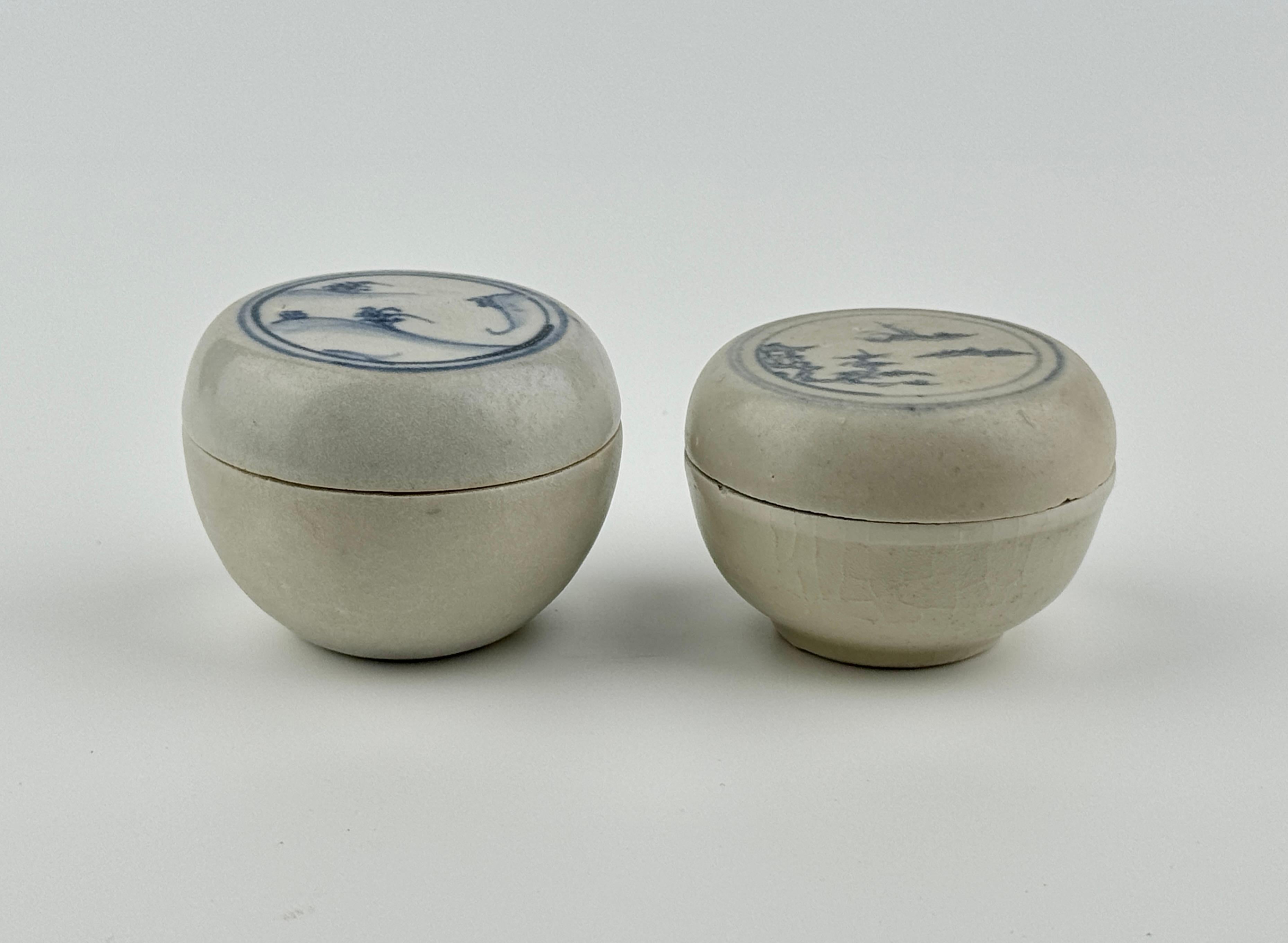 Boîtes couvertes vietnamiennes avec des motifs scéniques représentatifs. Toutes deux sont constituées d'une base de couleur crème et de motifs bleus, typiques de la poterie annamite. Ces caractéristiques communes mettent en évidence le savoir-faire