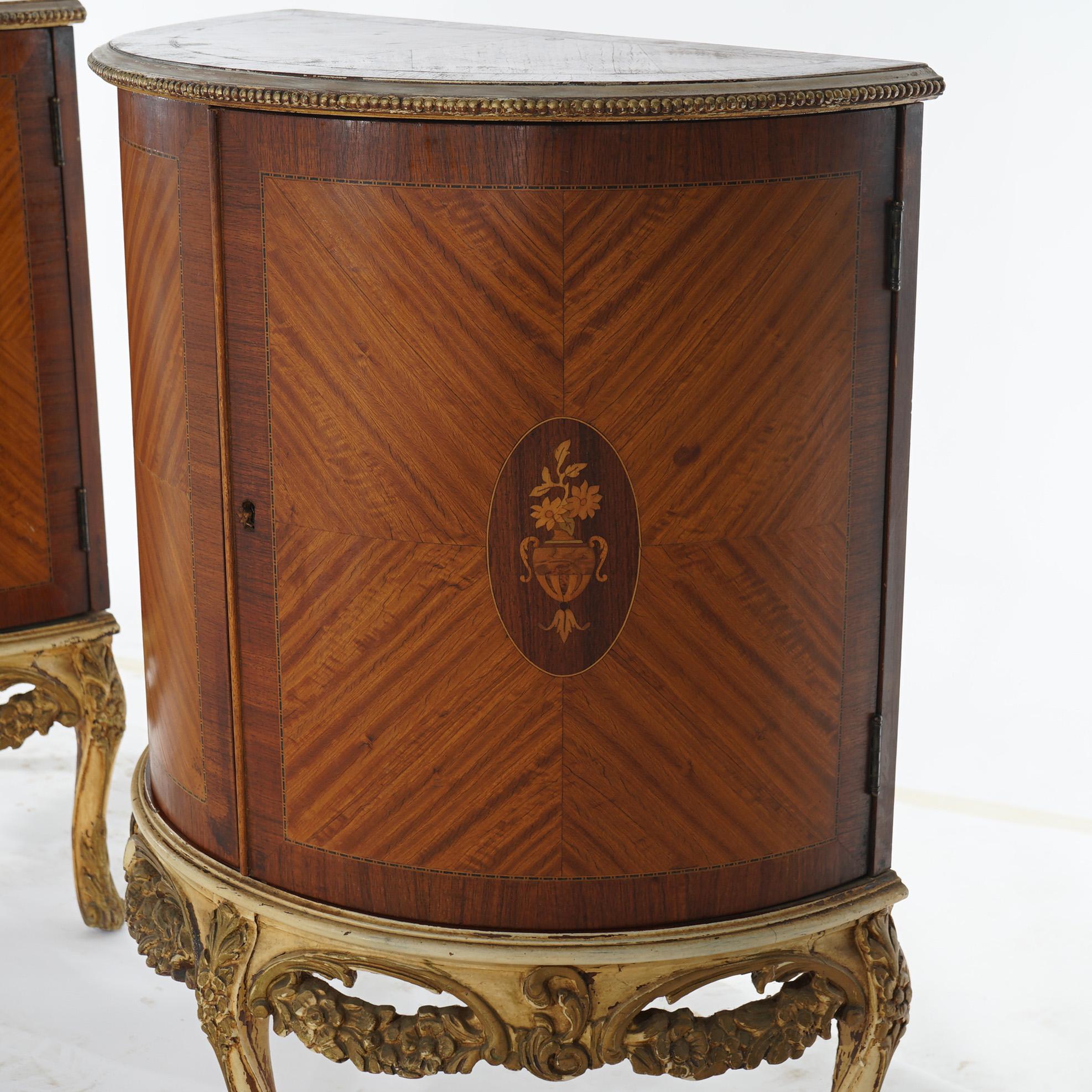 An antique pair of French side stands offers demilune form with satinwood facing and having floral marquetry medallion, double curved doors opening to shelved interiors, garland form apron and raised on cabriole legs, c1920

Measure - 29