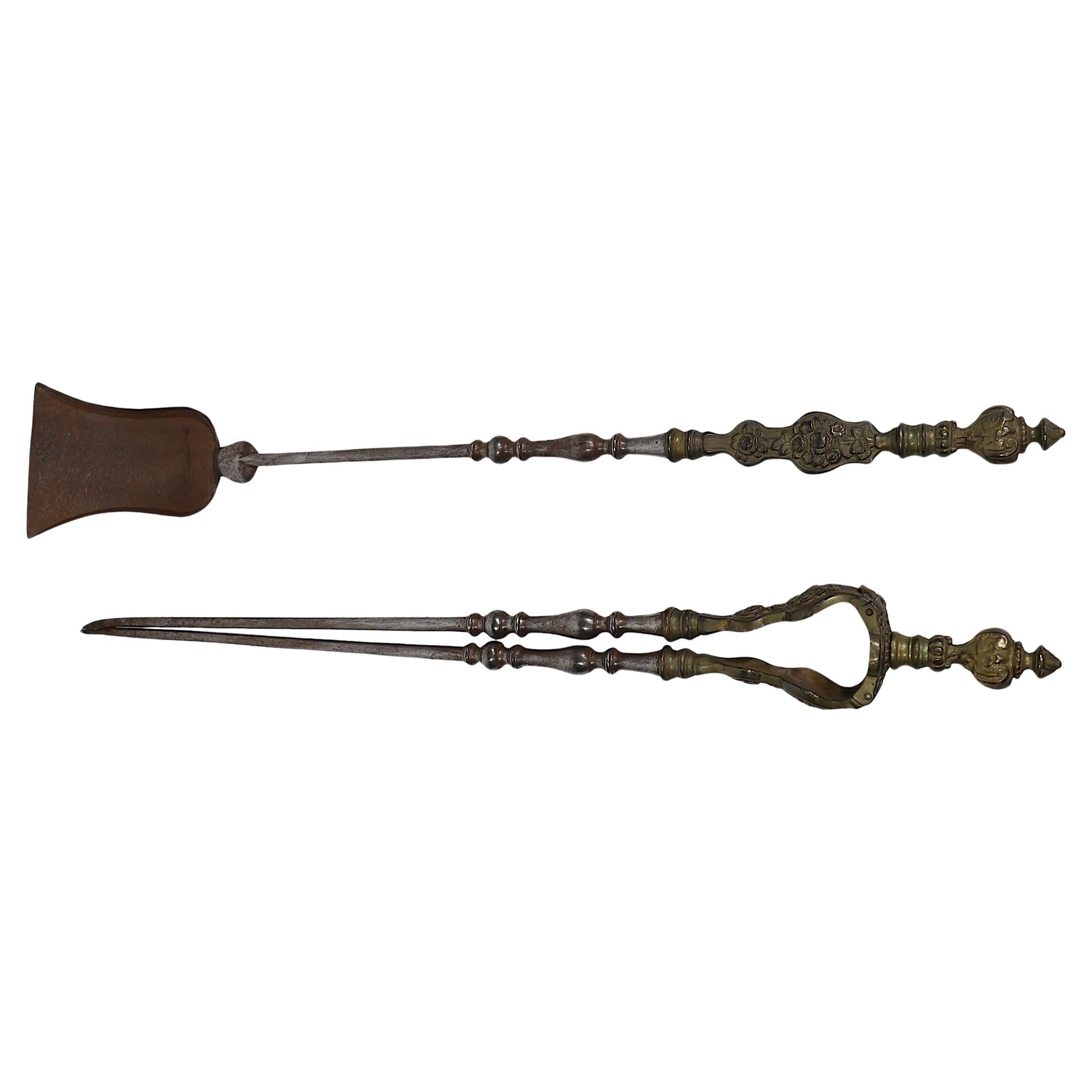 Two exquisite antique fireplace tools, a tongs, and a shovel, both having finely detailed cast brass handles, with elegant polished steel tools. 
 We especially love the jointed mechanism that the tong tool has. 
 We believe these are French in