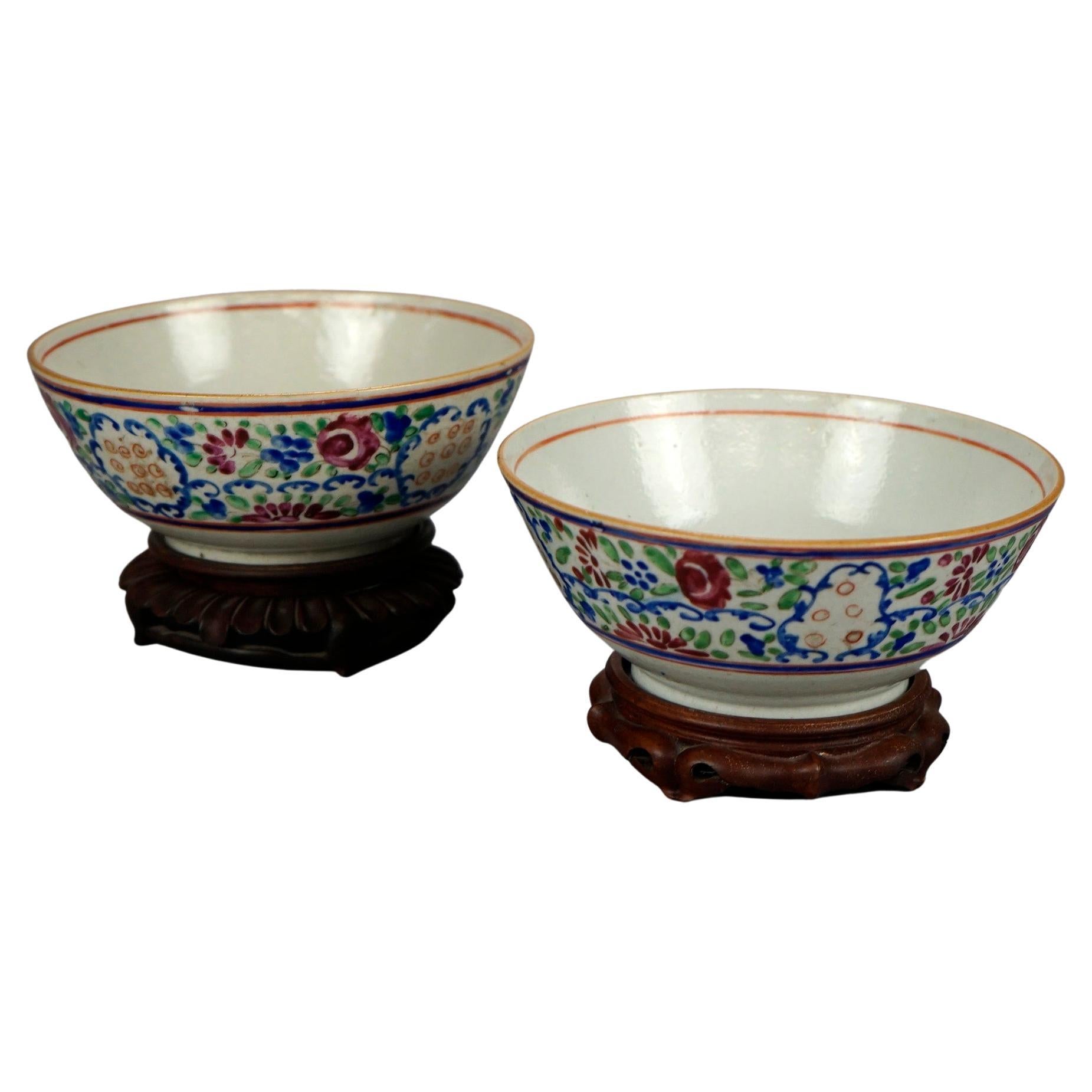 A pair of antique Chinese rice bowls offer porcelain construction with hand painted floral design and raised on carved hardwood stands, 19th century

Measures- 4.25''H x 6.75''W x 6.75''D (base 1.25''H x 4.5''W x 4.5''D).
 