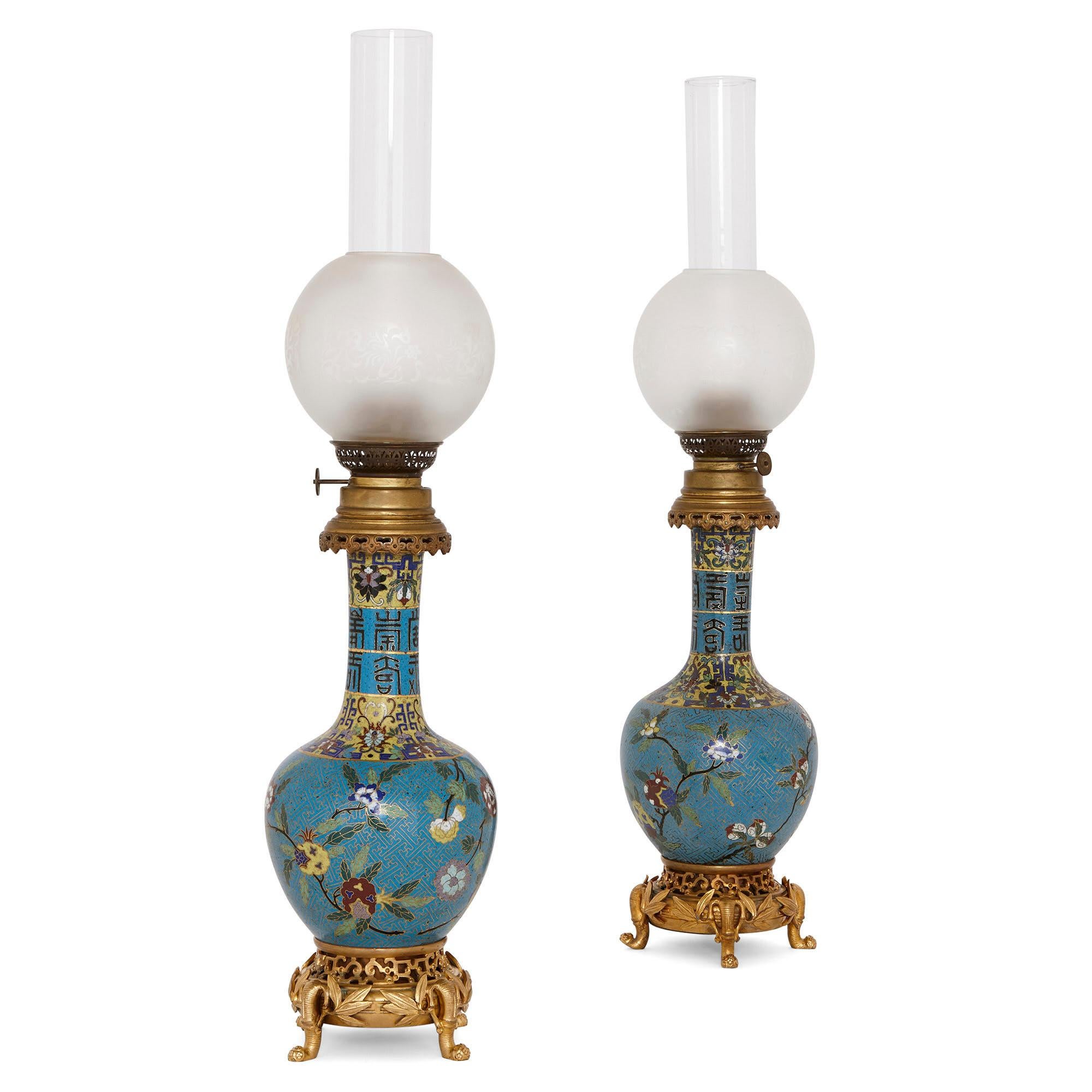 These beautiful oil lamps were created in France in the late 19th century. They are designed in a wonderful chinoiserie style—a European take on Chinese decorative arts. 

The lamps are identical in design. Each lamp features a burner which is
