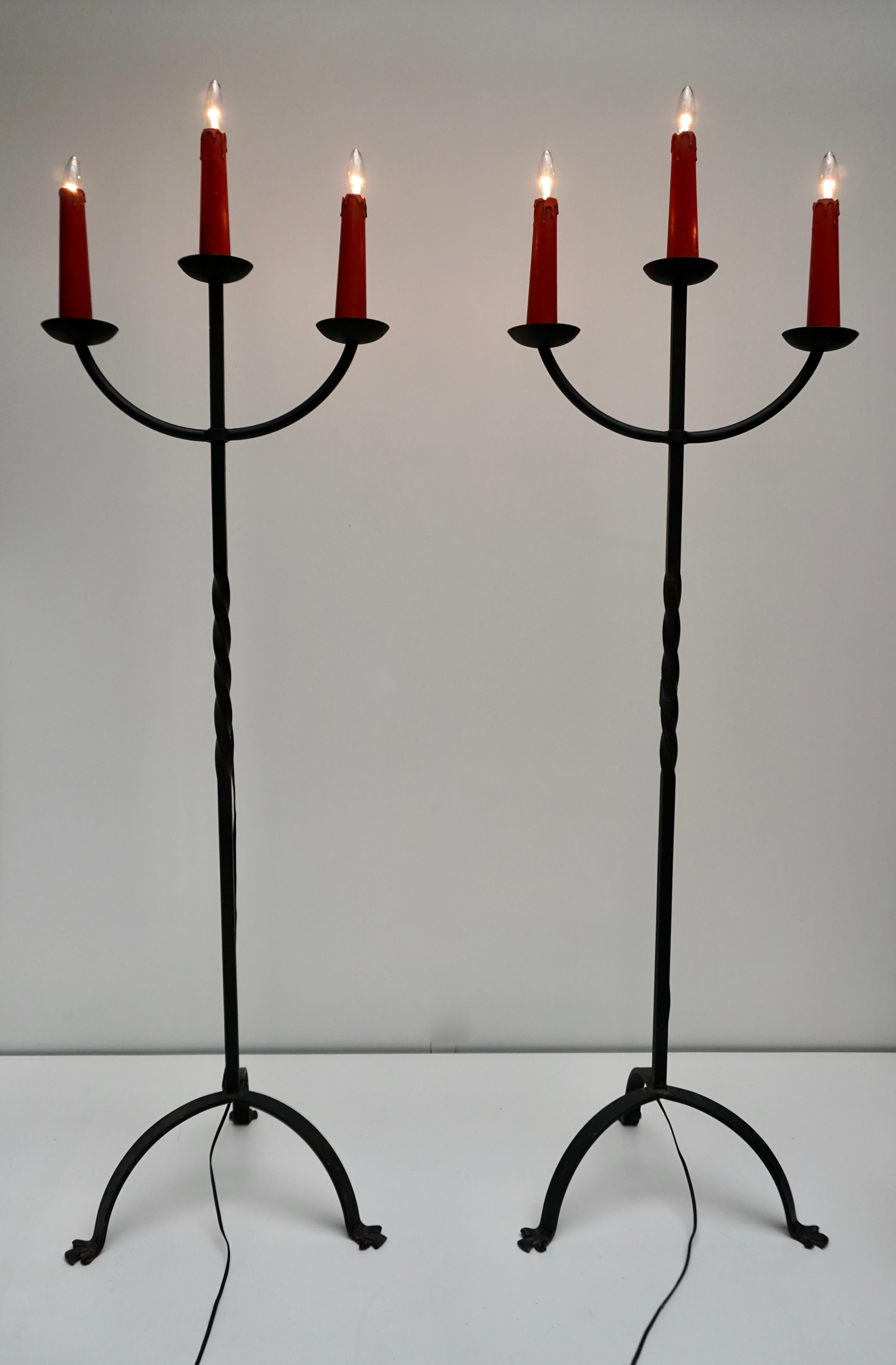 Direct from France.
Two gorgeous 3-light antique wrought iron floor lamp with candle holders, like an antique candelabra fresh out of a French country home or chapel! Three deep metal cups each hold a faux wax candlestick over the wired sockets.