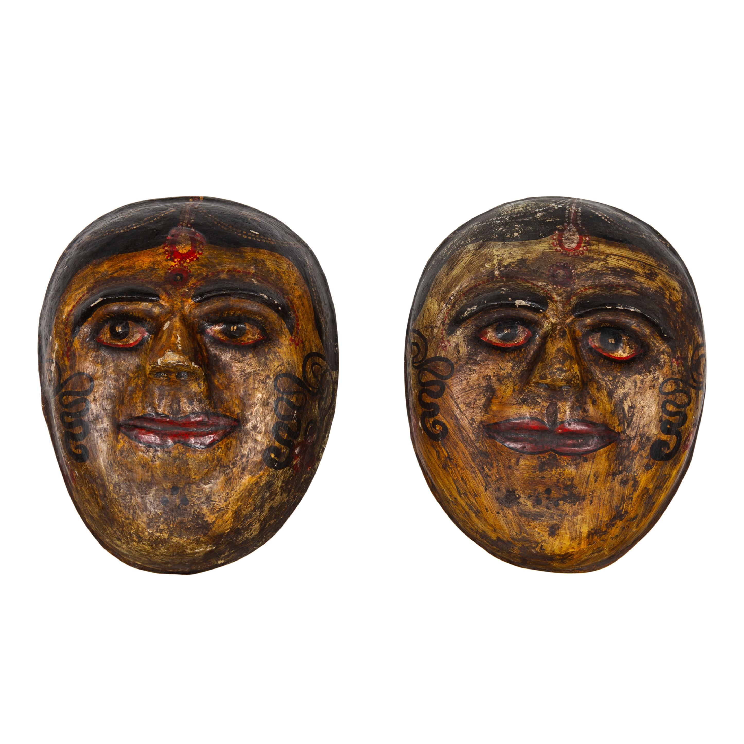 Two antique Indian papier-mâché hand painted face masks from the early 20th century, depicting Indian brides. They are priced and sold individually. Featuring a polychrome finish made of ocher, red and black tones, each of these face masks depicts