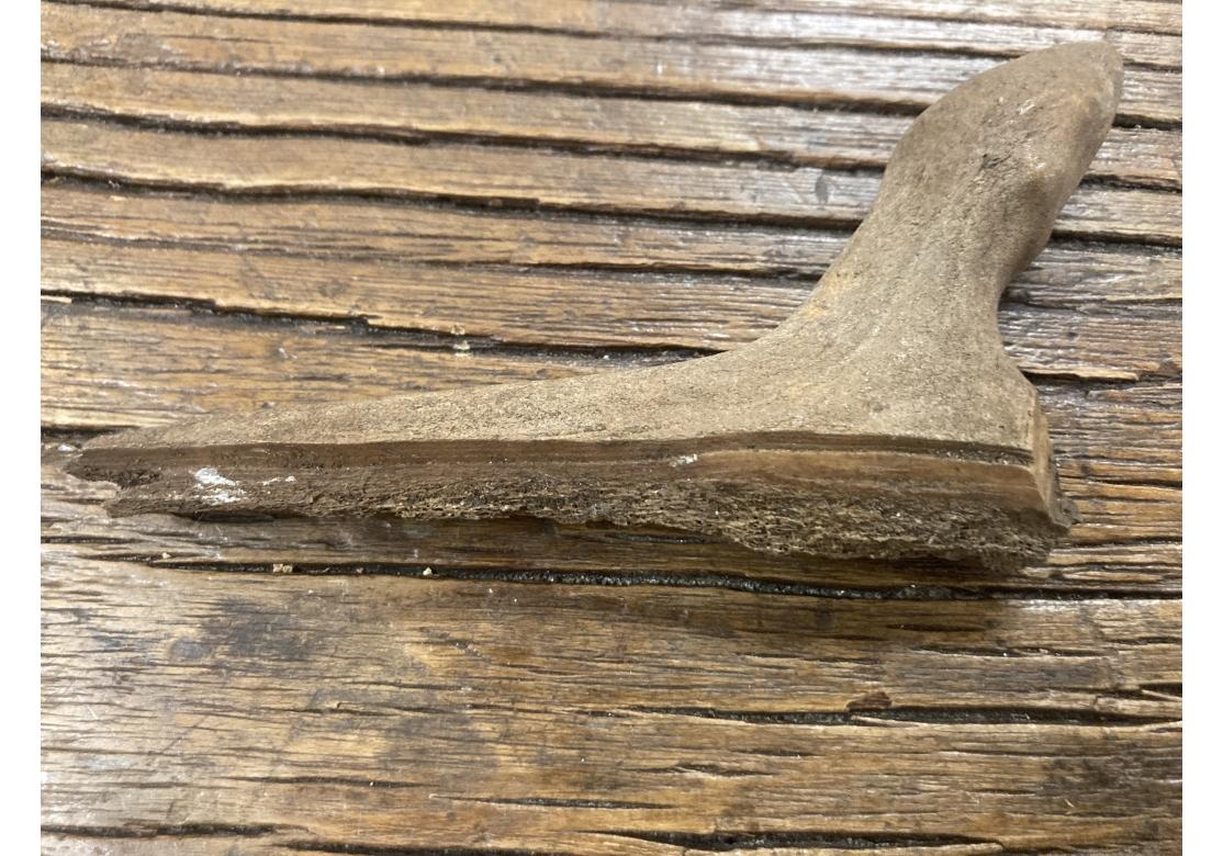 Deux poignées d'outils inuits du XIXe siècle ou peut-être antérieures, l'une en bois sculpté et l'autre en os sculpté. La poignée en os porte la forme caractéristique d'une tête de phoque renversée, animal favori des Inuits. Le manche en bois est