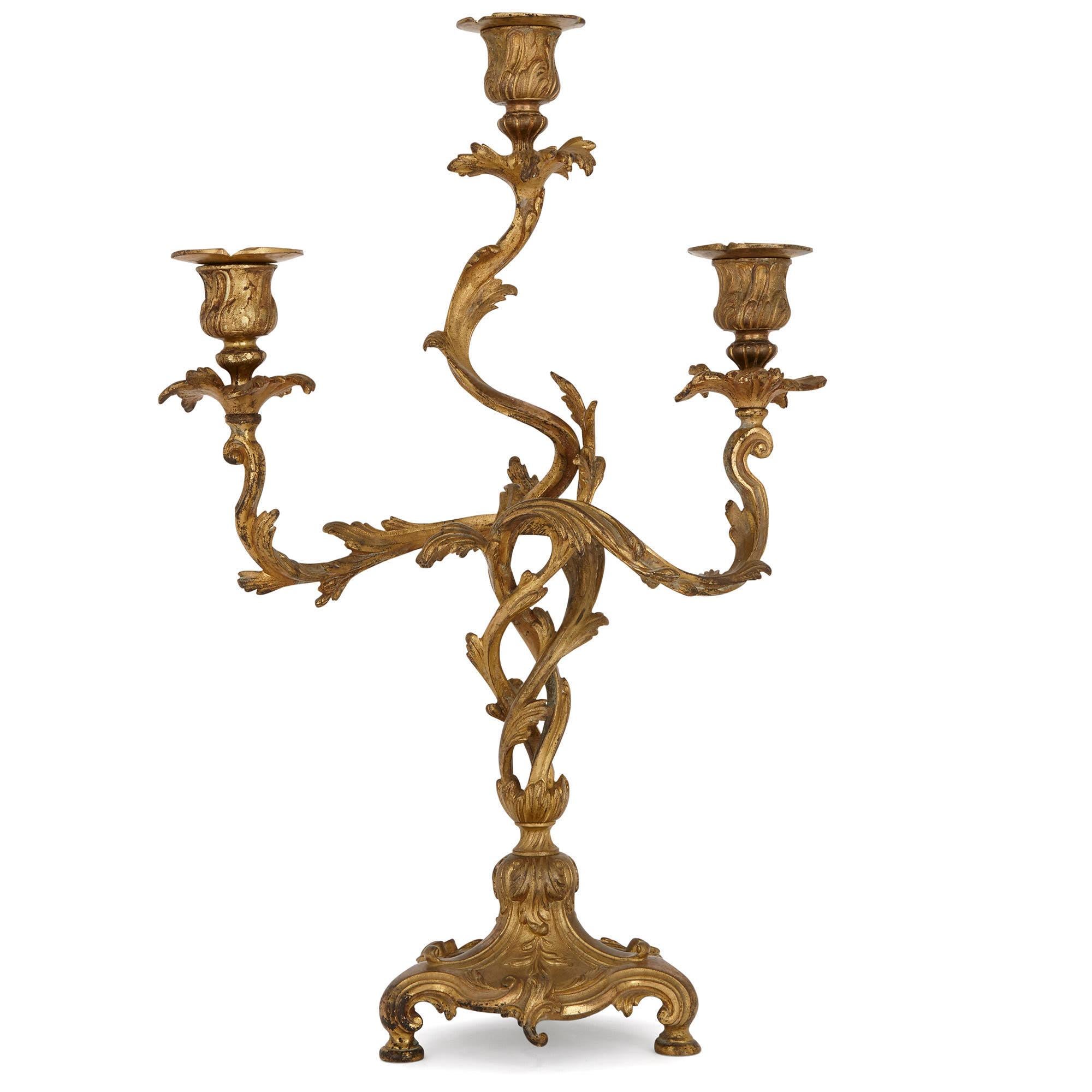 These beautiful gilt bronze (ormolu) candelabra are designed in a Rococo style, after decorative arts of the Louis XV period (1715-1774). The candelabra display many characteristics of the Rococo style, including elegance, organic sinuosity and
